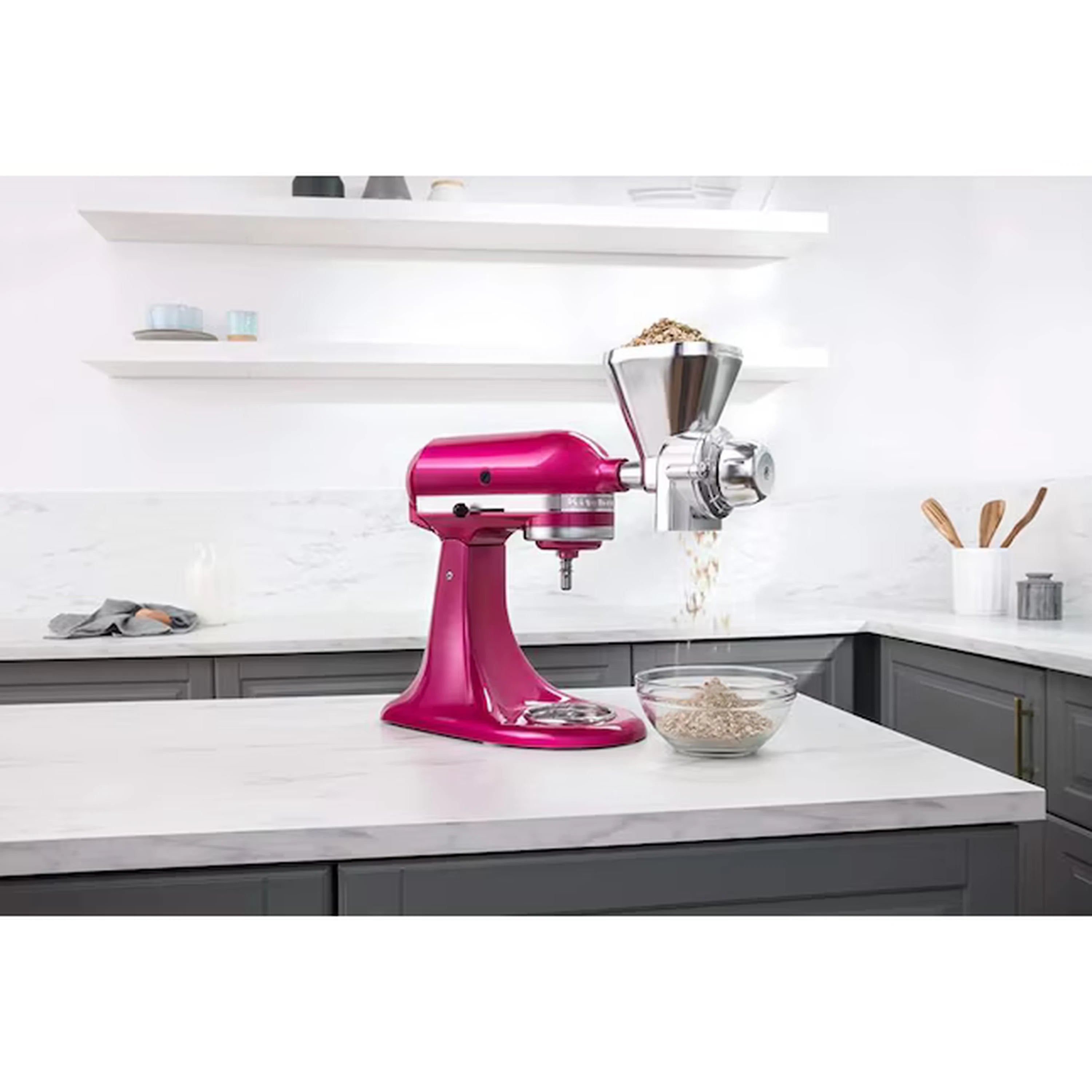Pink stand mixer grain mill attachment dispensing grain into hopper