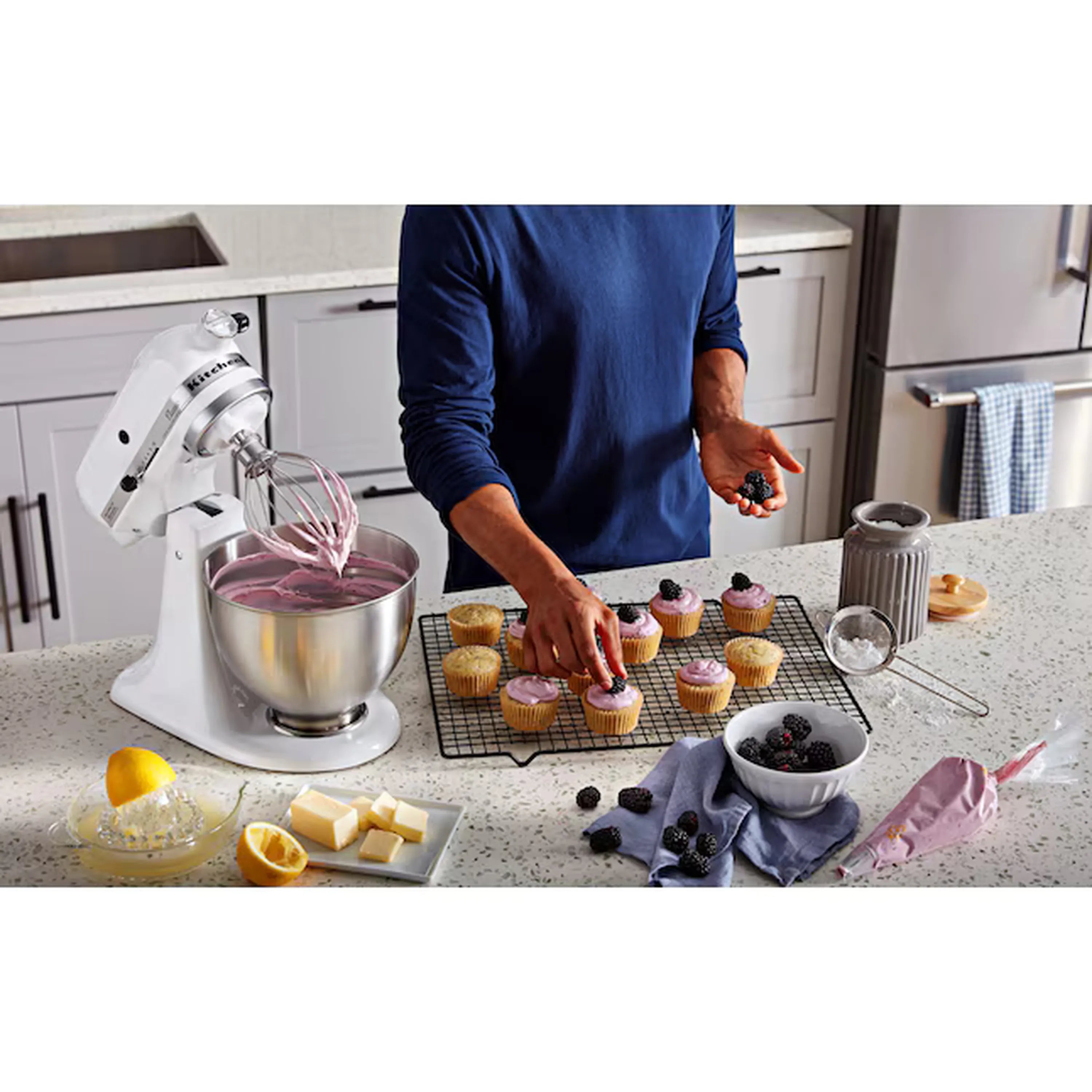 White stand mixer with stainless bowl beside baking items on counter