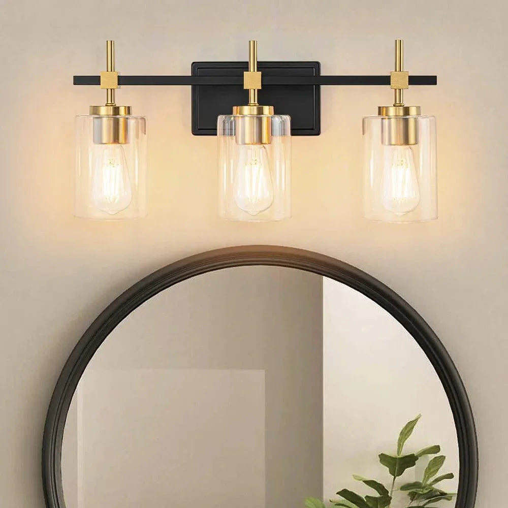 3-light bathroom vanity light lit, black frame with clear glass shades and gold accents