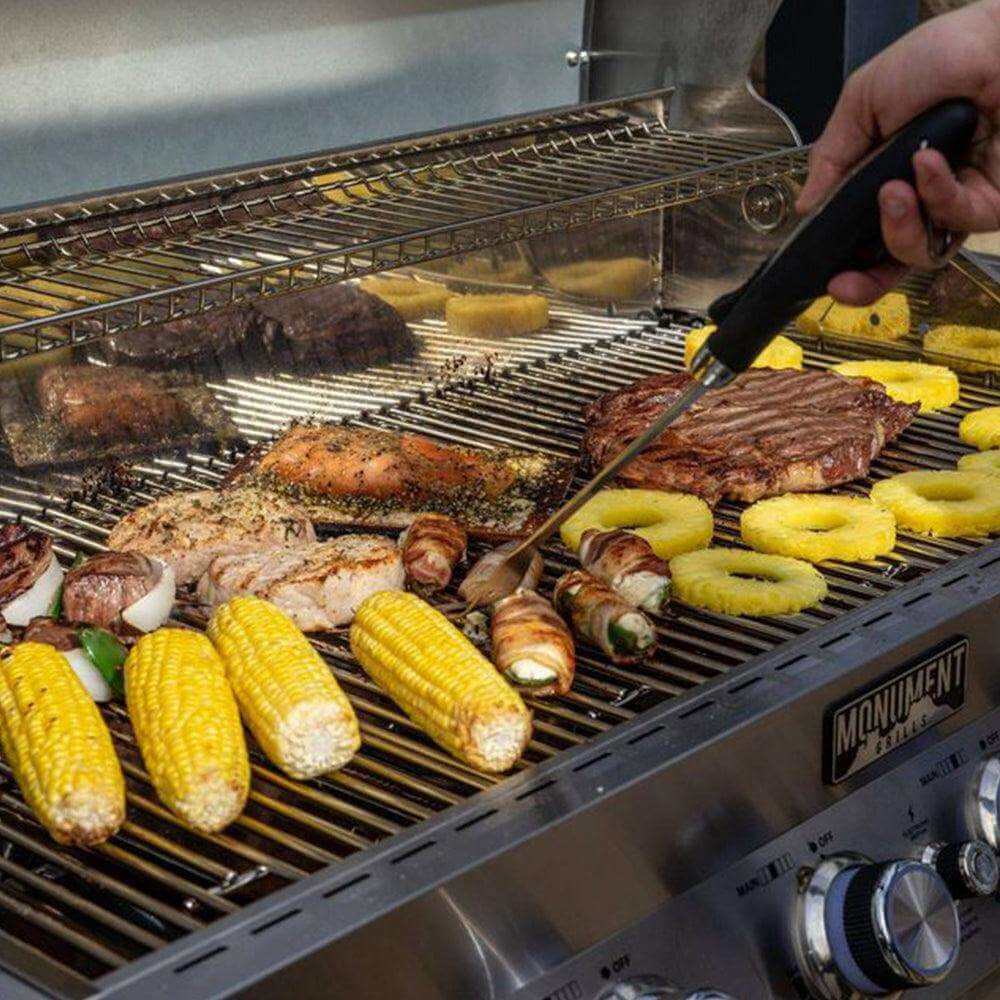 Stainless steel grill grate with grilled meats, corn, and pineapple rings