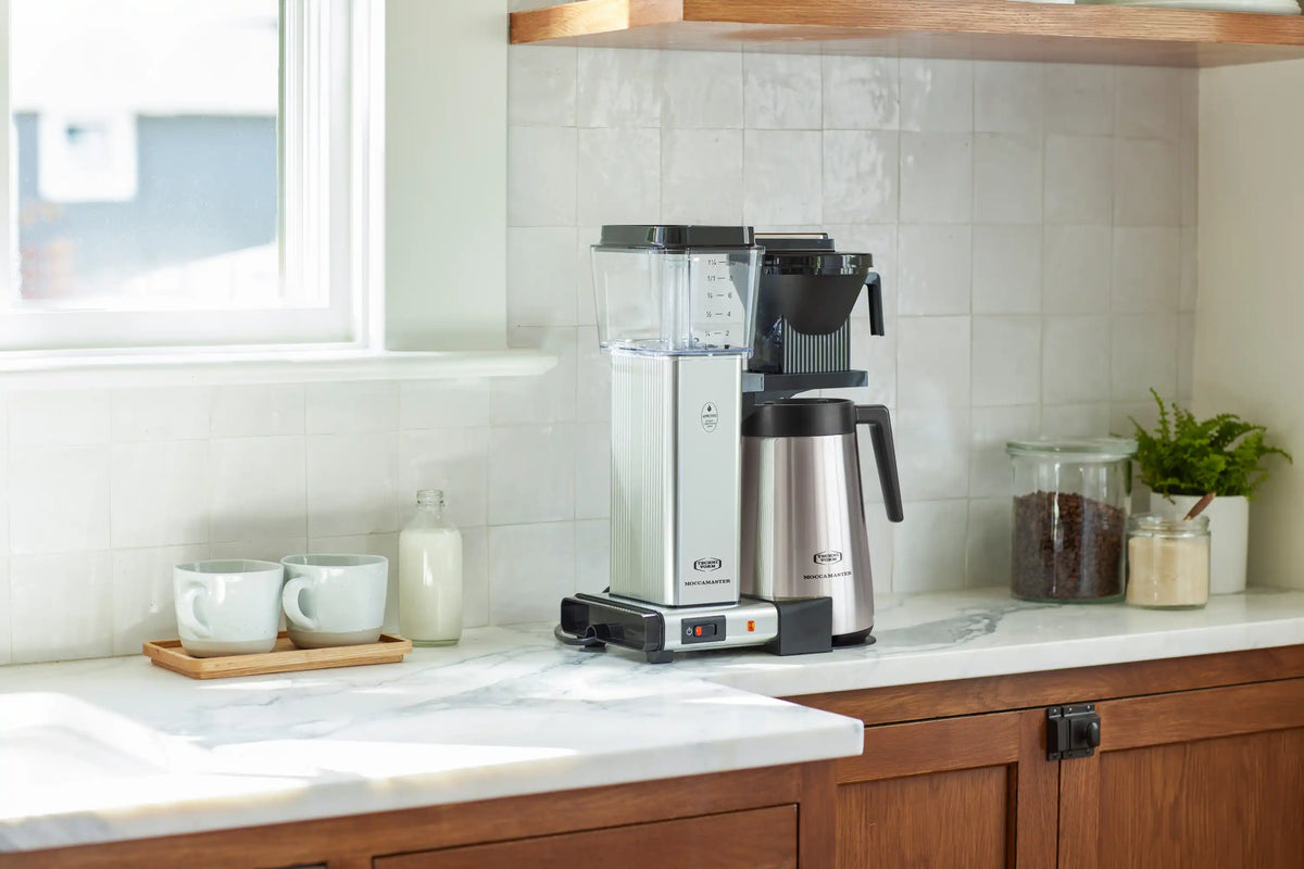 Moccamaster coffee maker on countertop with silver thermal carafe and black brew basket