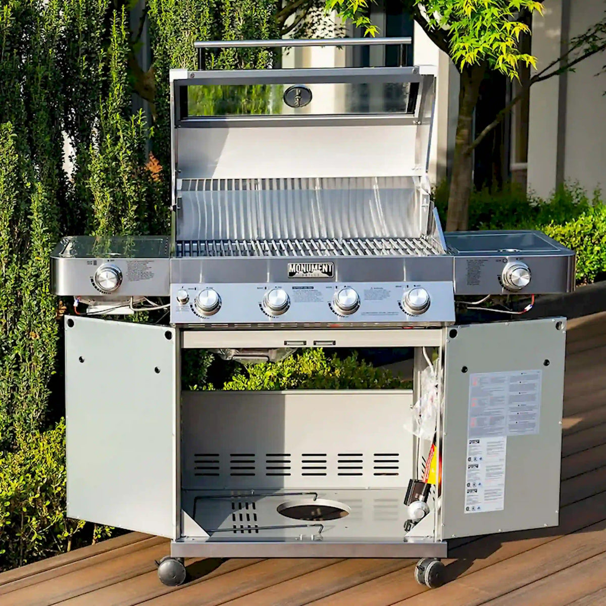 Stainless steel propane grill with open lid, grates, and front cabinet access panel