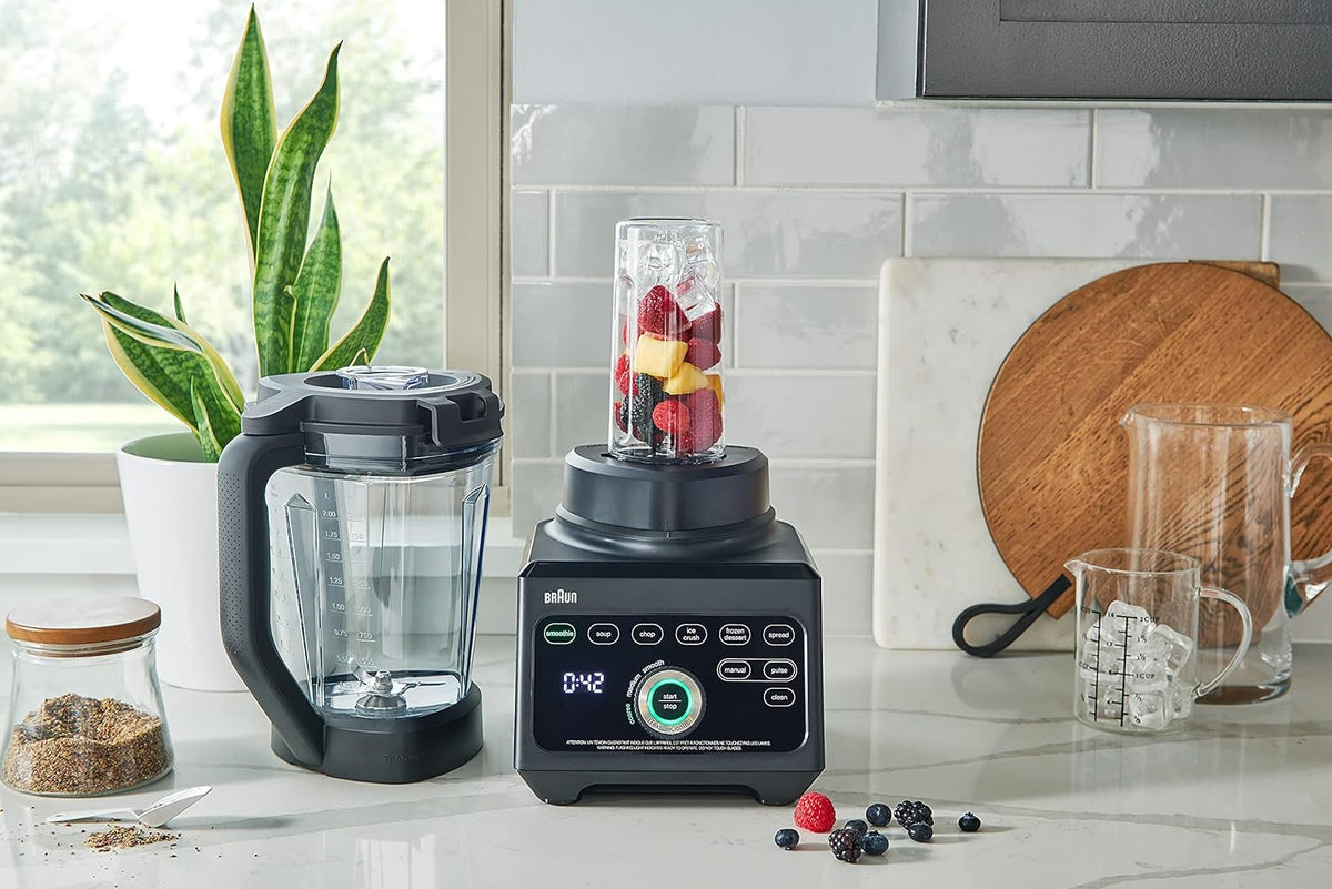 Braun blender with clear jar and black base, with ingredients and utensils nearby