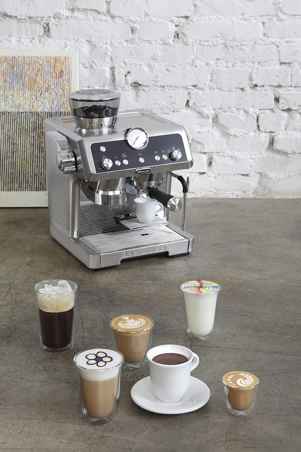Clear double wall latte macchiato glass with coffee and foam, on countertop near machine