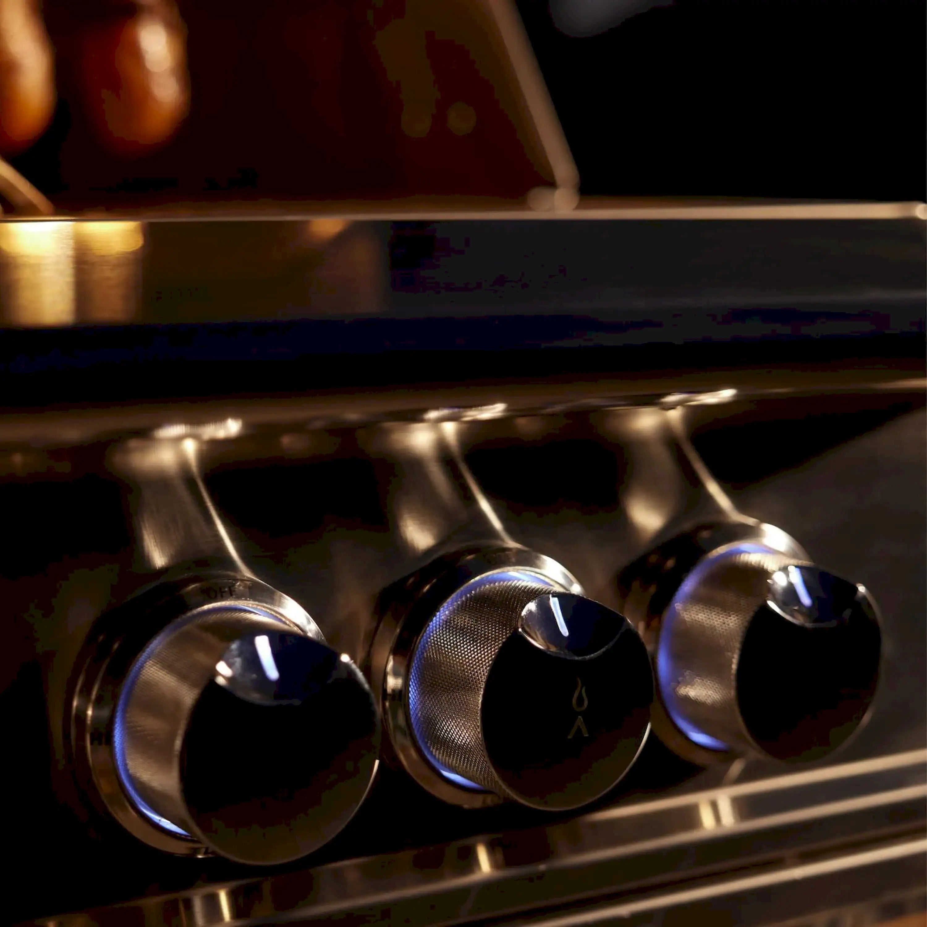 Gas grill control knobs with perforated burner caps on stainless panel