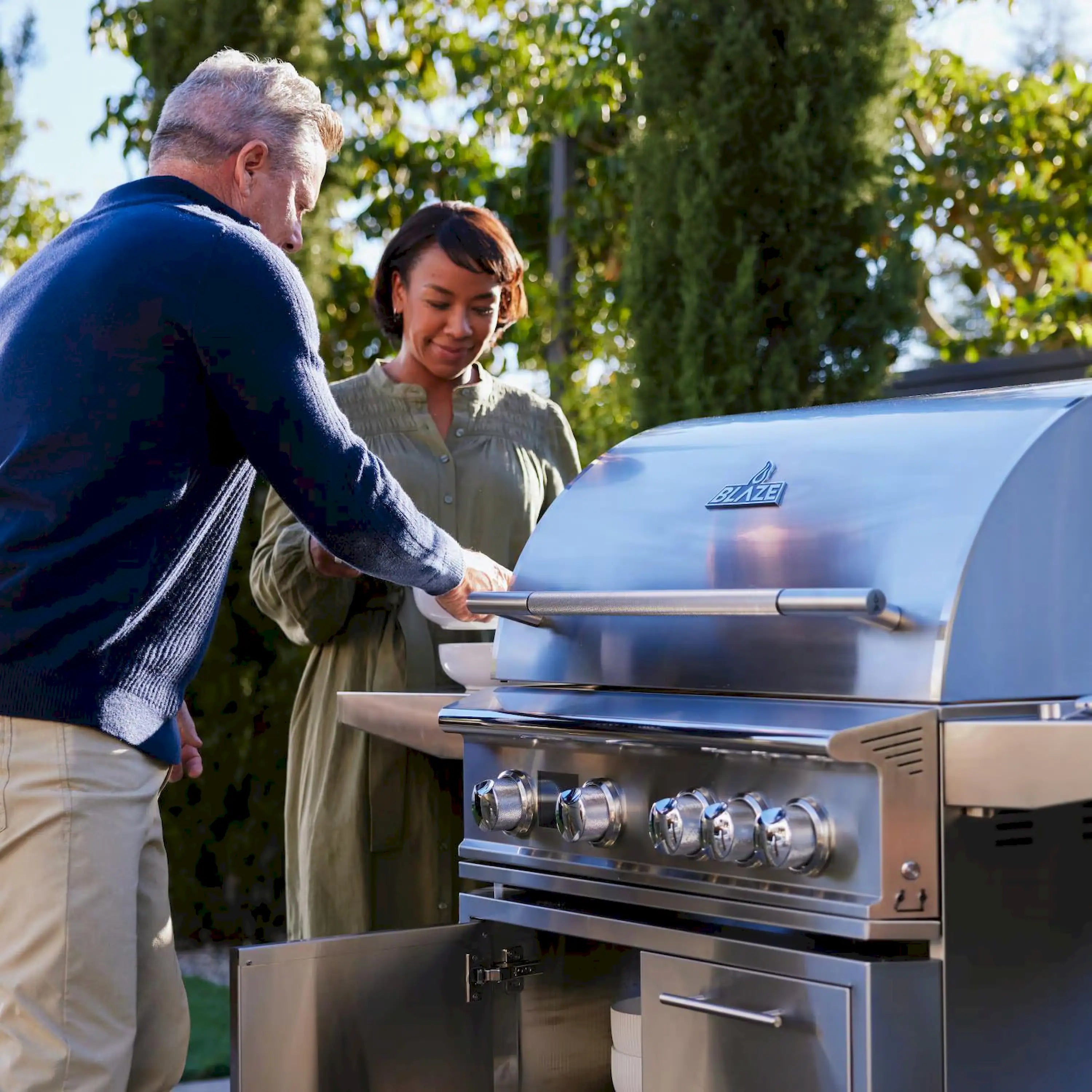 Stainless steel propane grill with open lid, four burners and front knobs