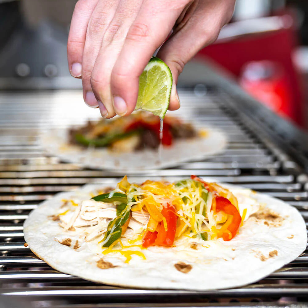Stainless steel cooking grid with grilled food and toppings on it