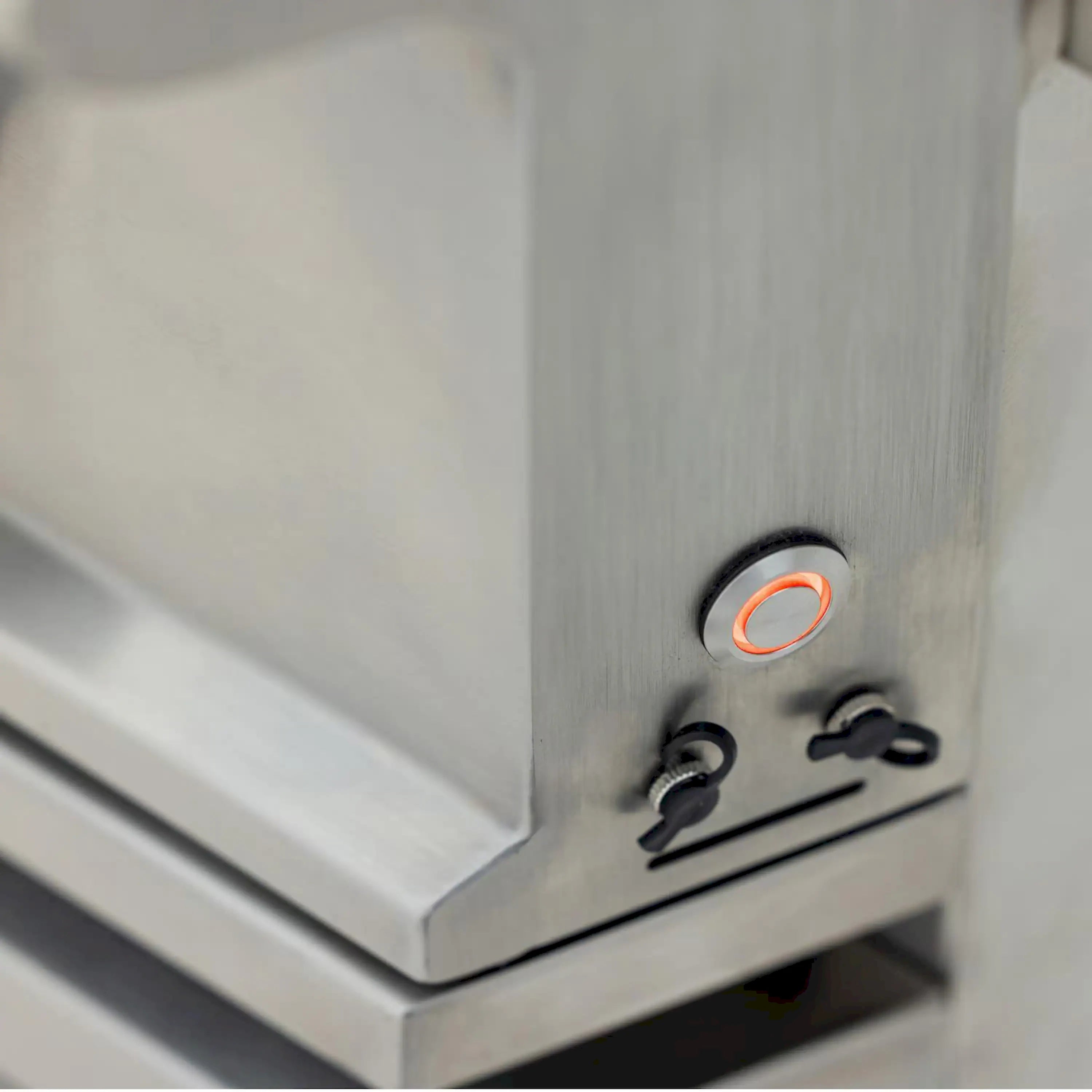 Stainless natural gas grill control panel with glowing knob and burner controls
