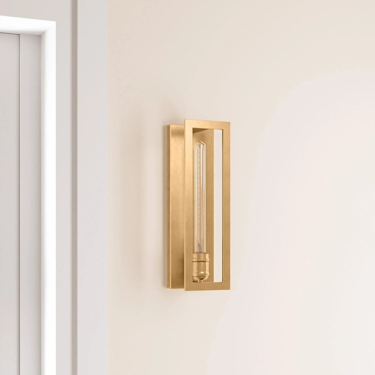 Golden wall sconce with clear vertical glass tube bulb mounted on light wall