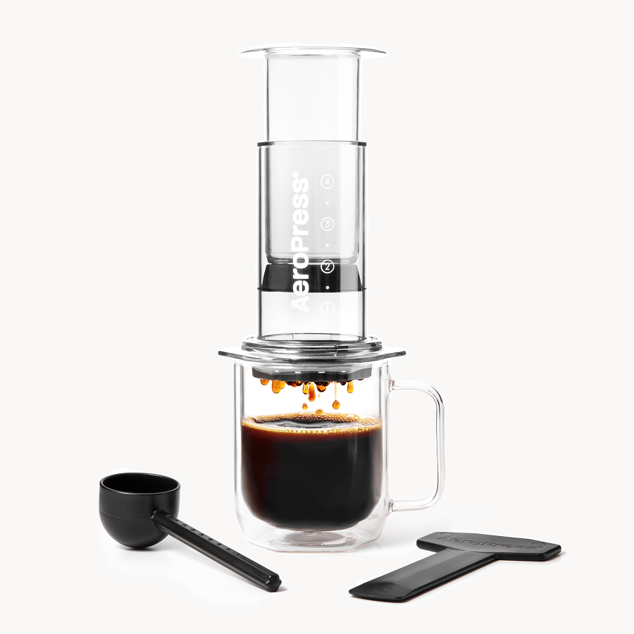 Clear AeroPress coffee maker with black scoop and two-piece brewing base