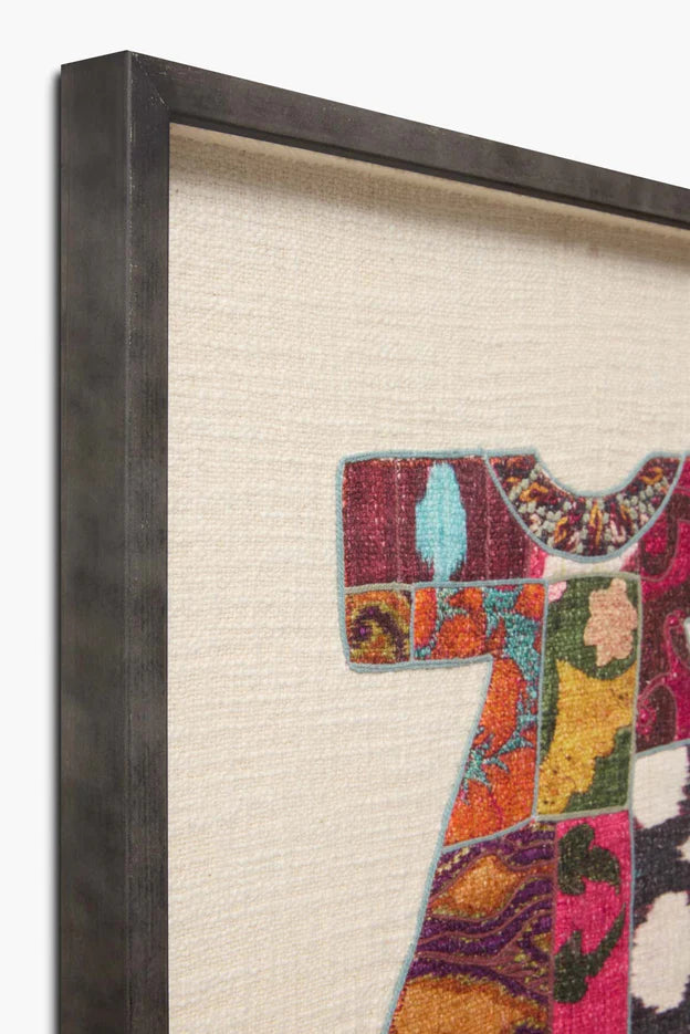 Ivory embroidered wall art rug, patchwork dress motif in dark frame, close-up