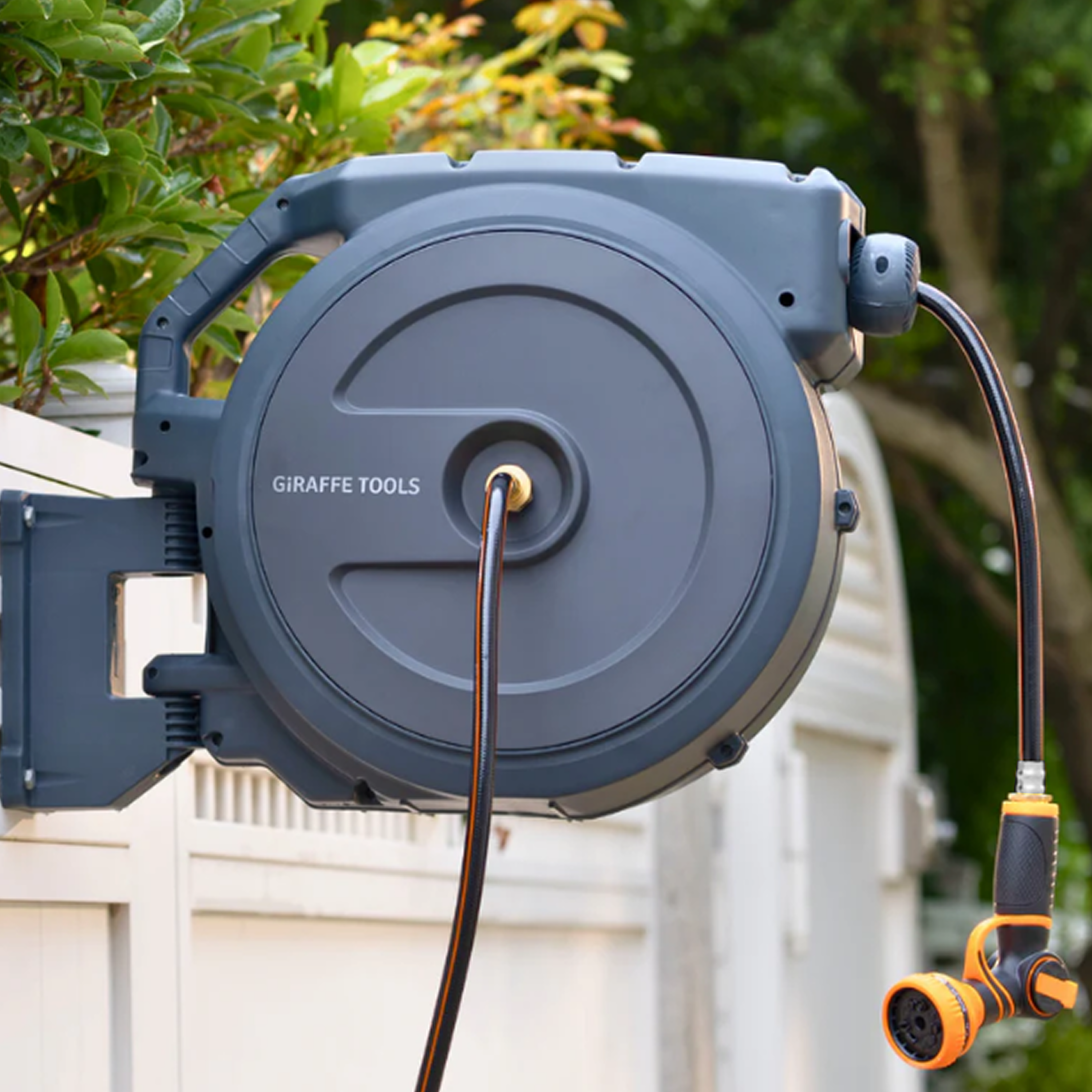 Retractable hose reel mounted outdoors in light blue-grey with connected spray nozzle