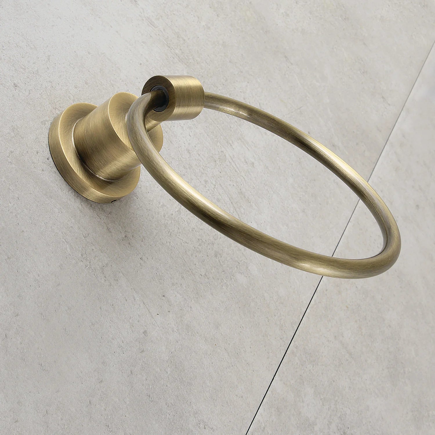 Wall-mounted antique brass towel ring with oval loop and circular backplate.