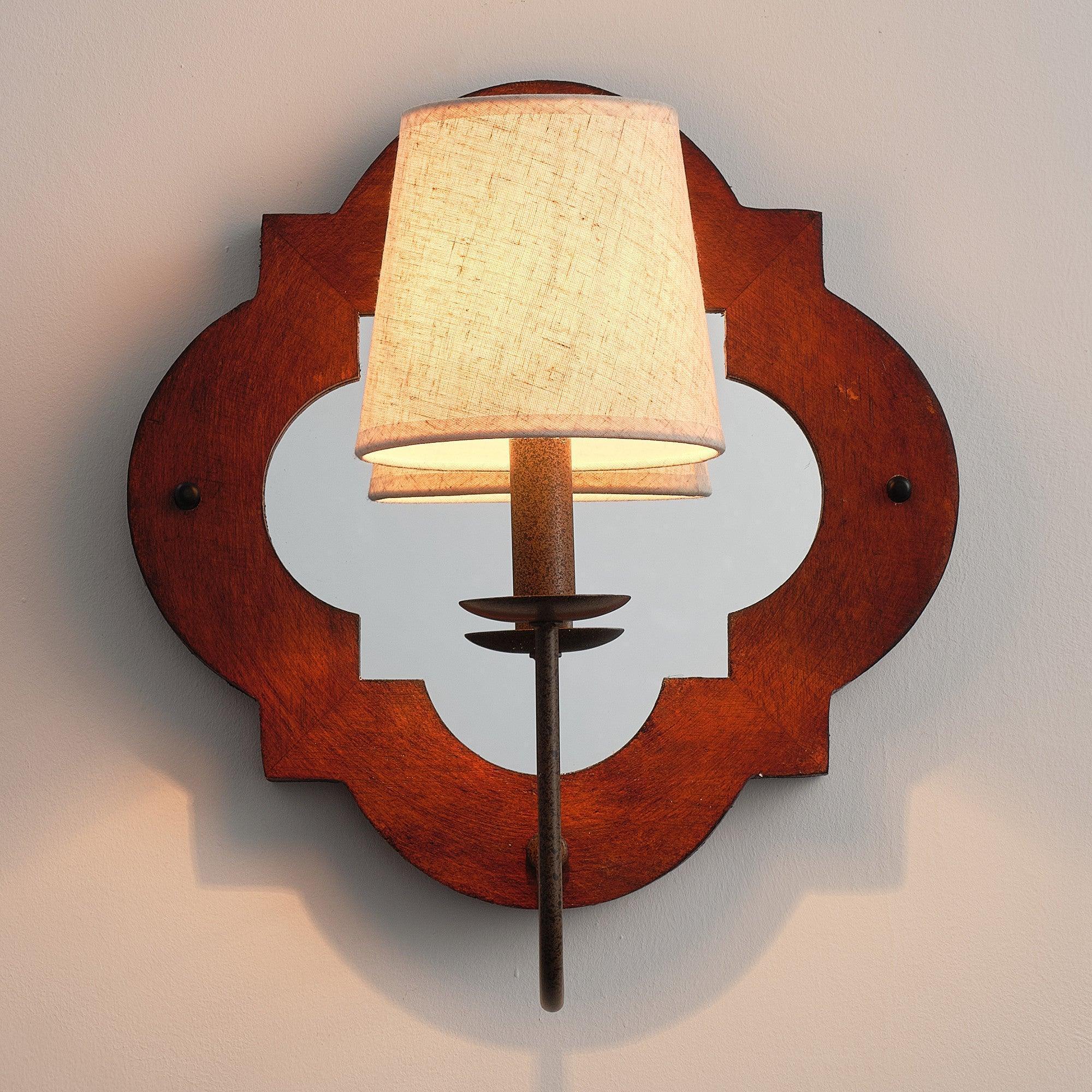 Brown wood wall sconce with two fabric shades and central metal post, rustic cutout design