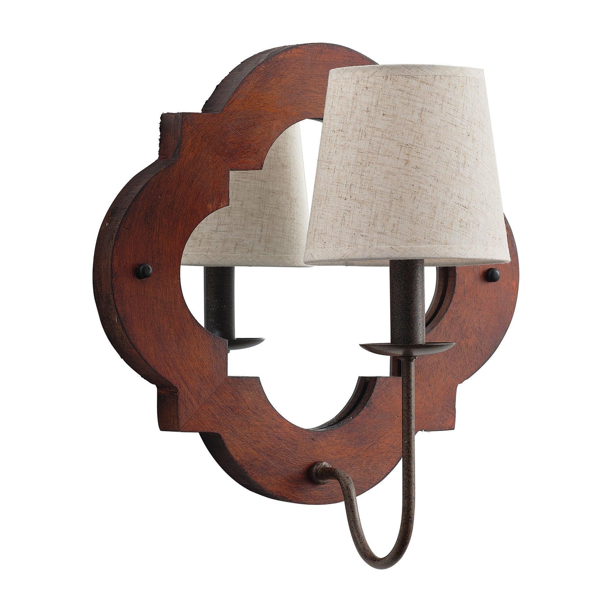 Brown wood wall sconce with two beige fabric shades and curved metal arms over cutout center