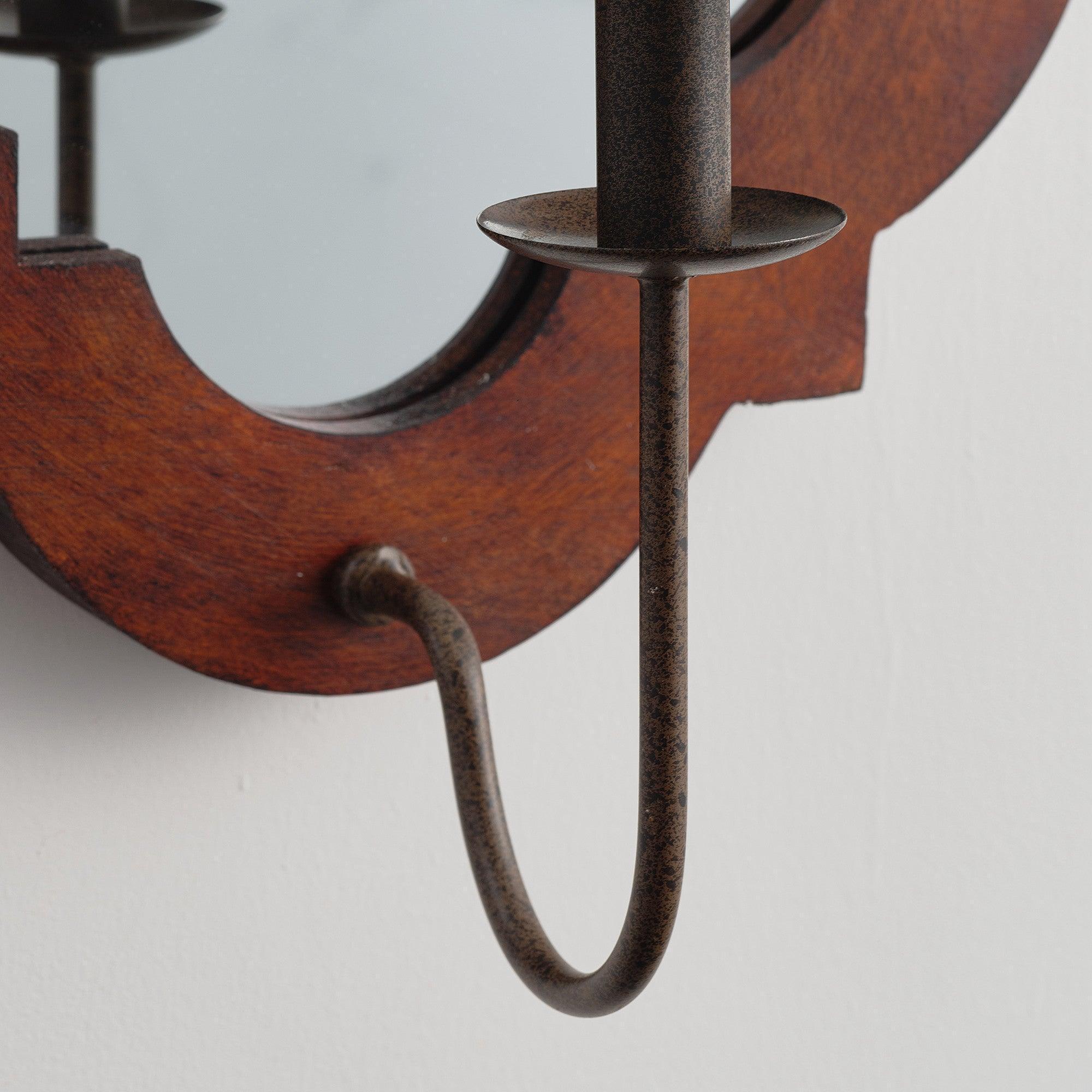 Detail view of brown wall sconce with curved metal arms and central dark metal lamp post