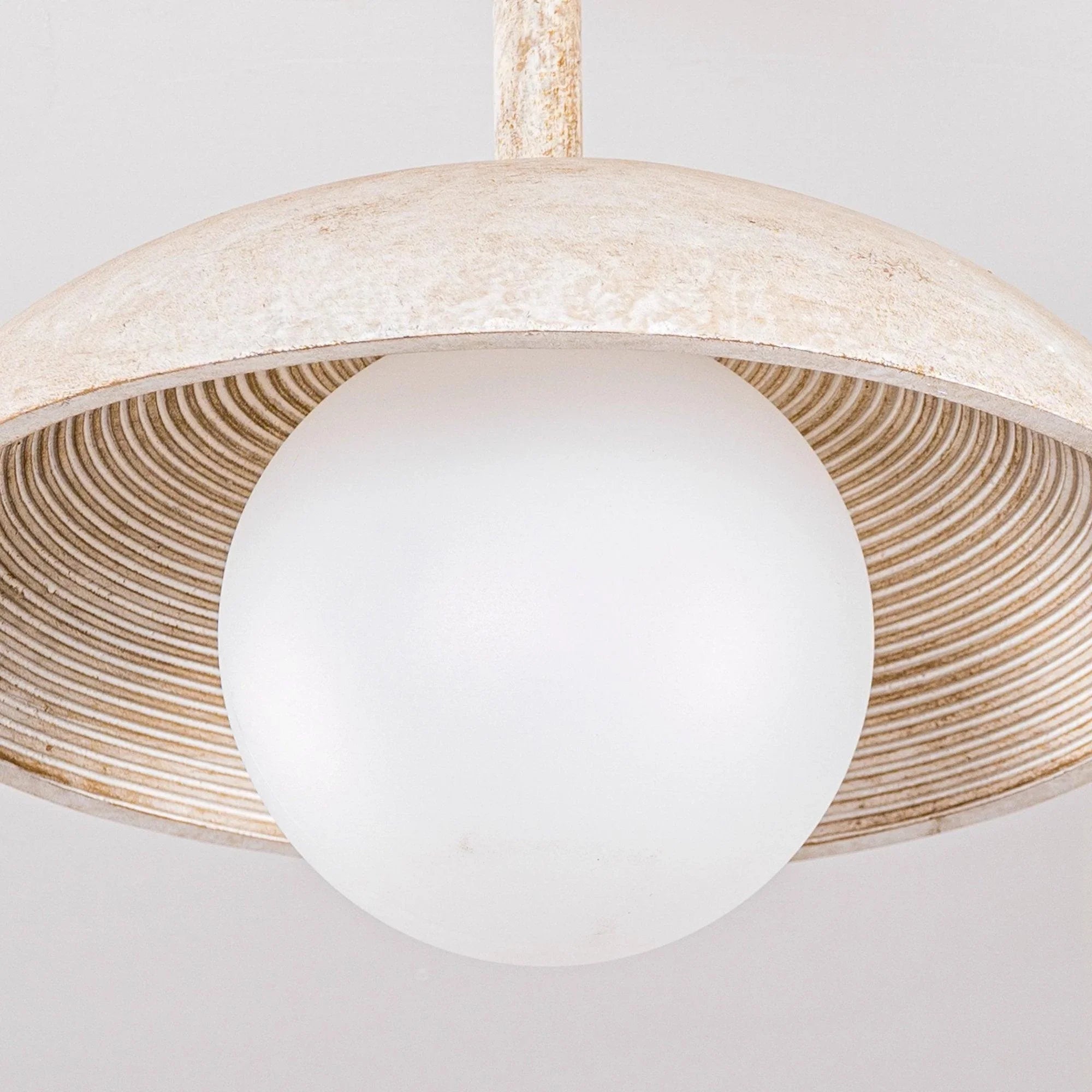 Pendant light close-up: frosted globe diffuser with ribbed metal outer shade