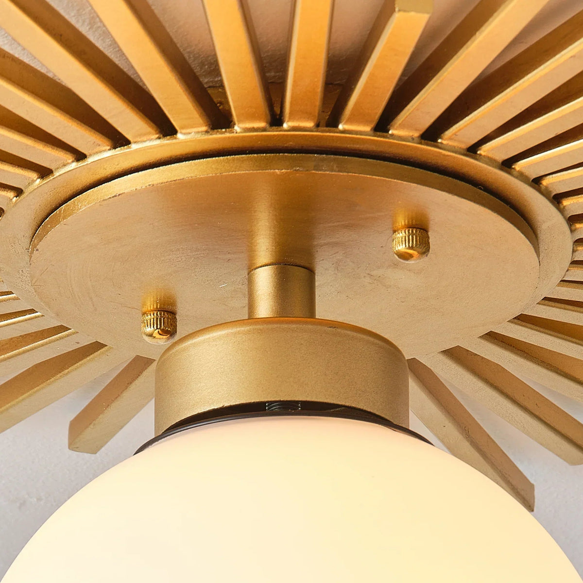 Close-up of golden mounting plate and frosted globe under sunburst metal rays