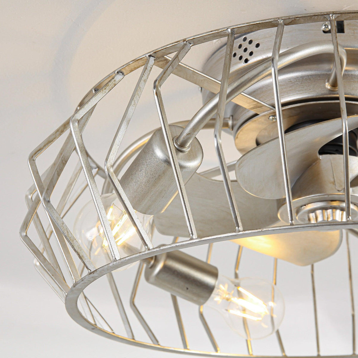 Close-up of silver flush mount fan motor housing and wire cage with bulbs
