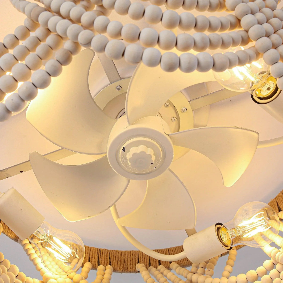 Low-angle view of a white beaded flush-mount ceiling fan with lit bulbs and blades