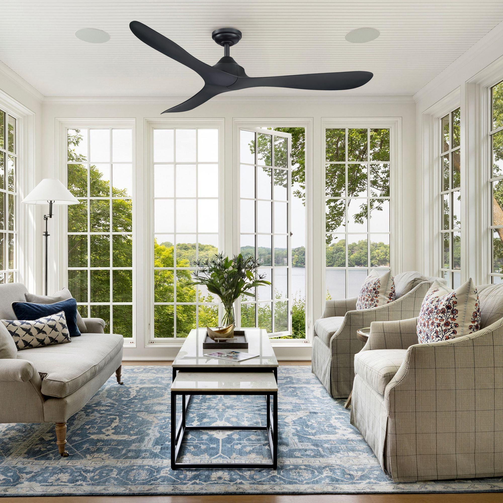Black modern ceiling fan with 5 blades on a ceiling in a bright living room.