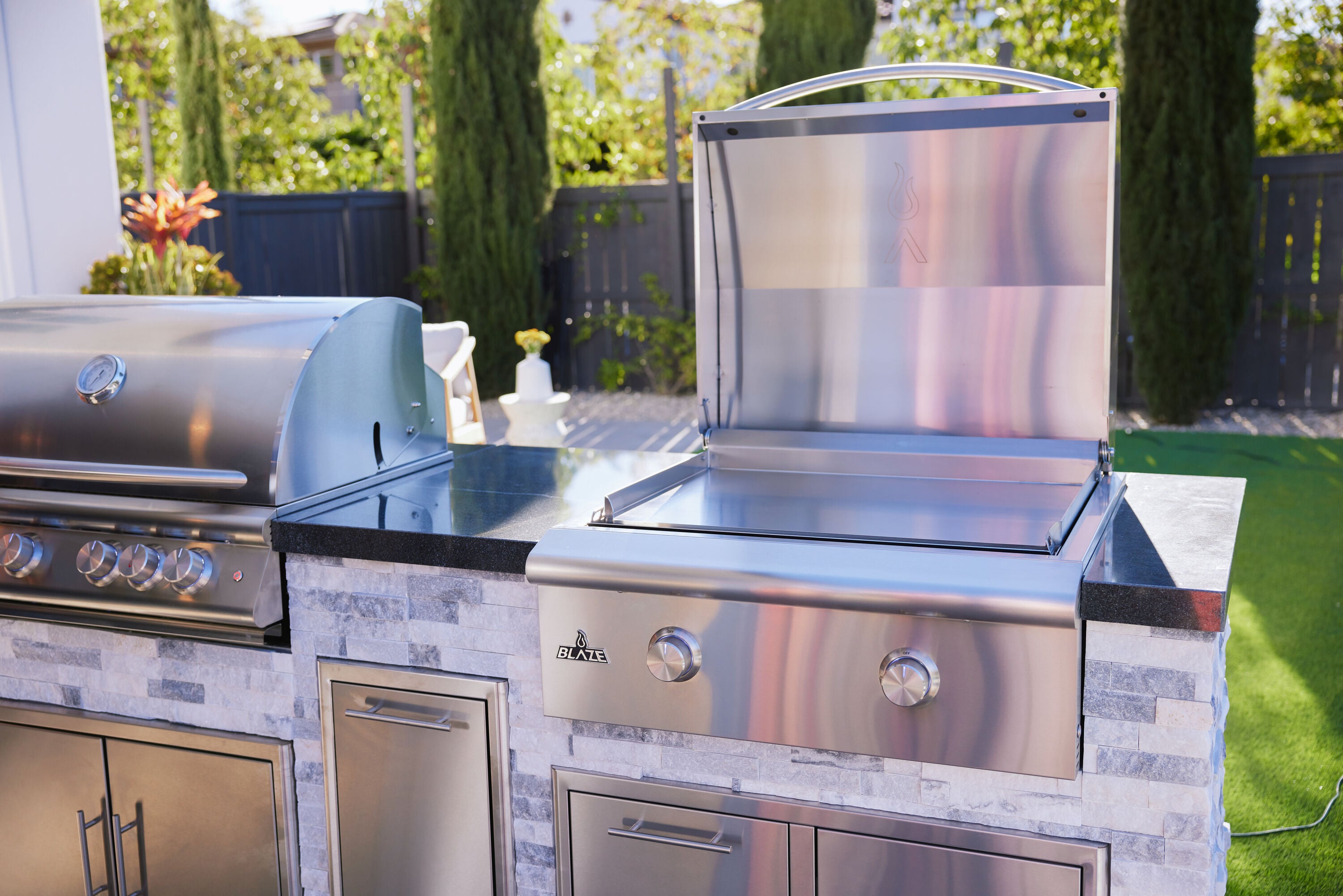 Stainless steel built-in propane griddle with lift-assist hood open and front control knobs