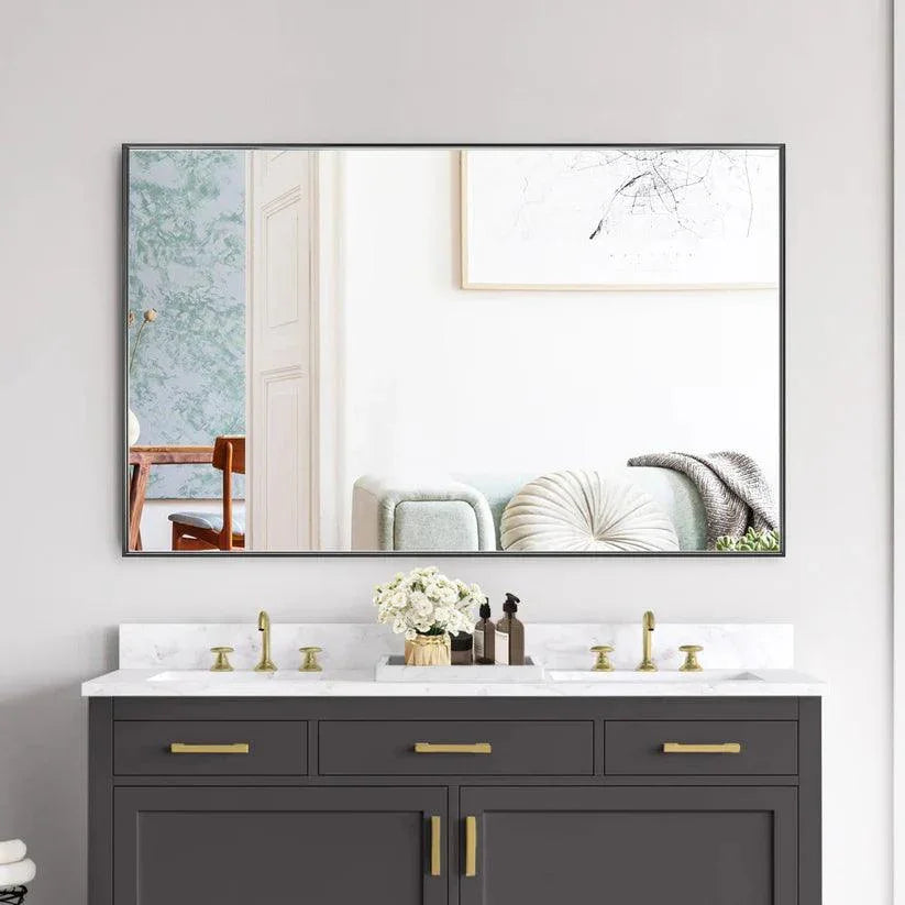 Rectangular wall mirror with black frame above dark vanity cabinets