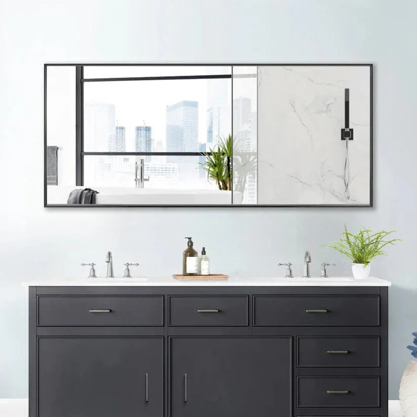 Rectangular wall mirror with black frame reflecting bathroom sink and window