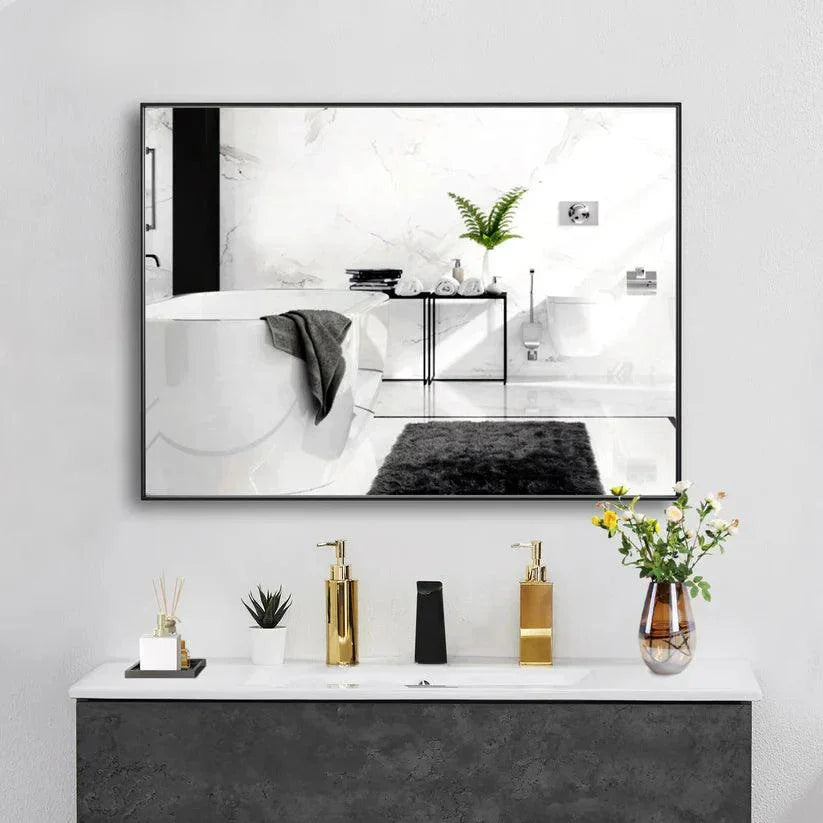 Black framed wall mirror with reflective glass over countertop with toiletries