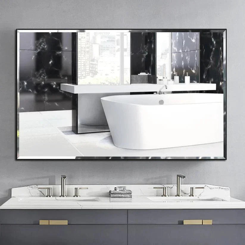 Black framed wall mirror with beveled glass edge reflecting a white freestanding bathtub.
