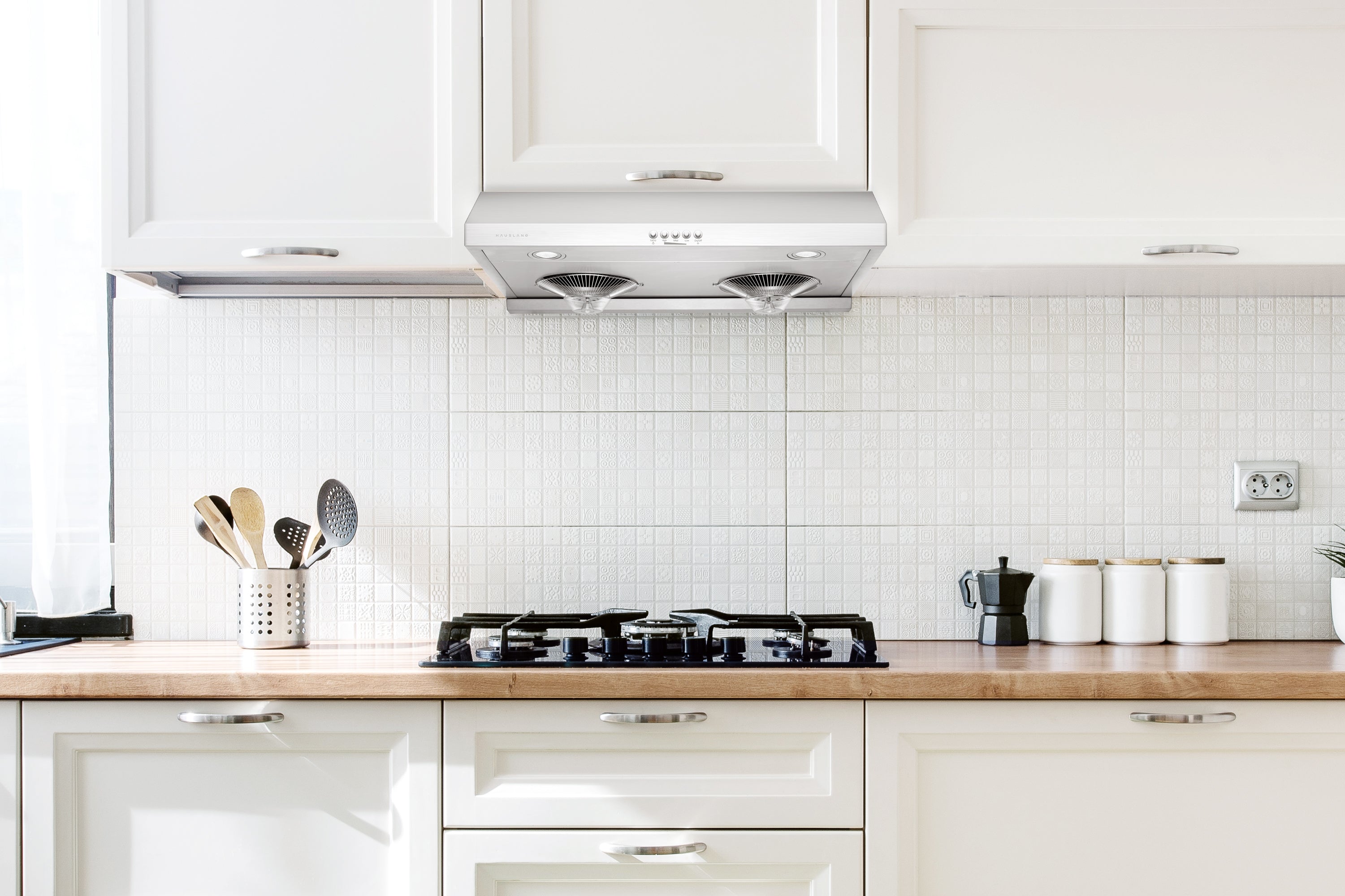 Stainless steel under-cabinet range hood installed above a cooktop with fan and lights