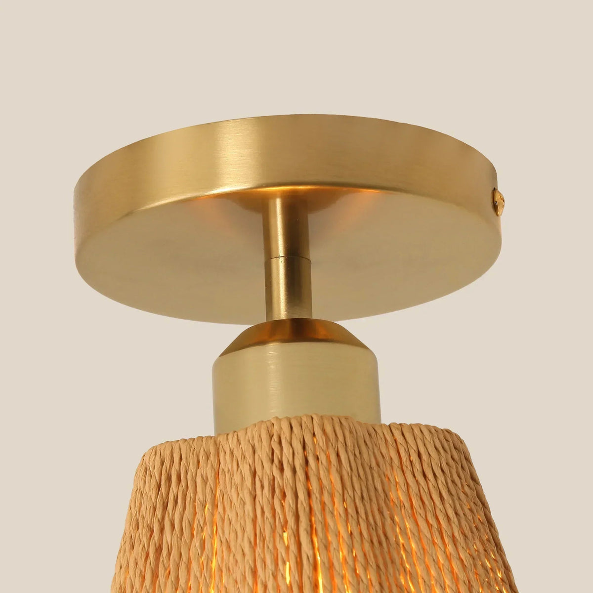 Golden ceiling light canopy and brass stem with textured jute-wrapped shade