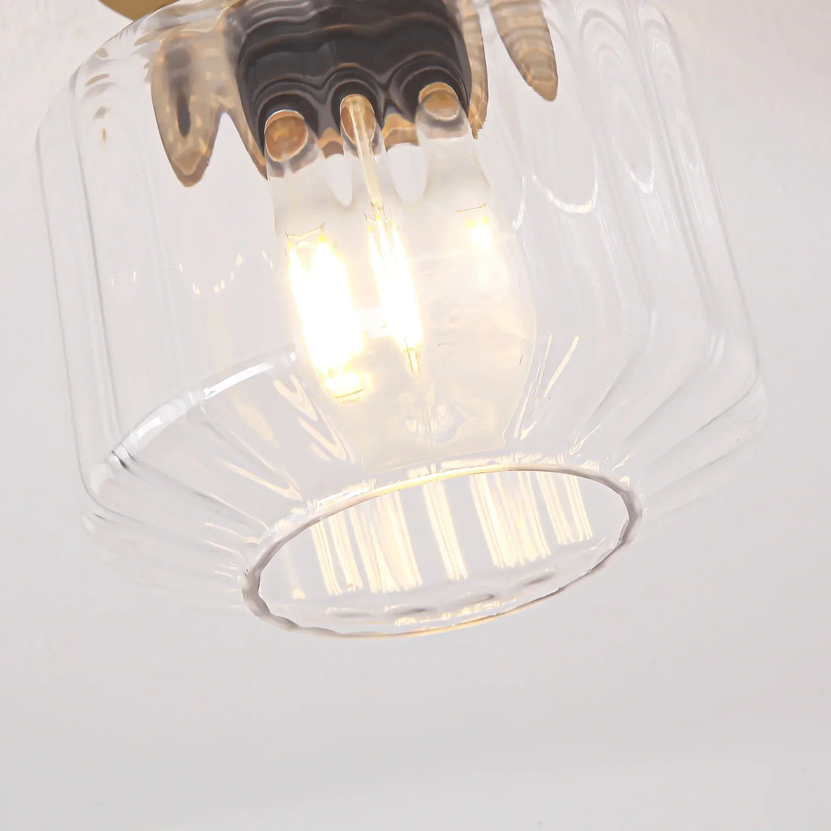 Clear glass ceiling light shade with illuminated bulb and metal mounting plate