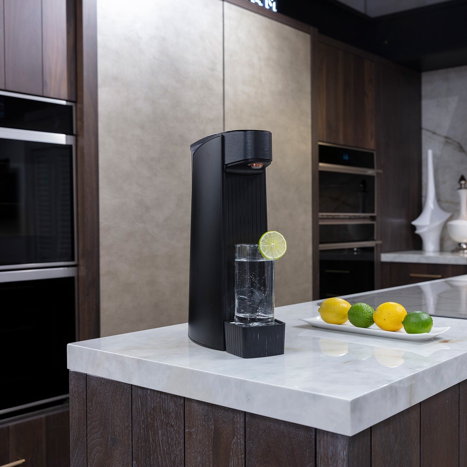 Black sparkling water maker dispensing water into a clear glass with lime slice