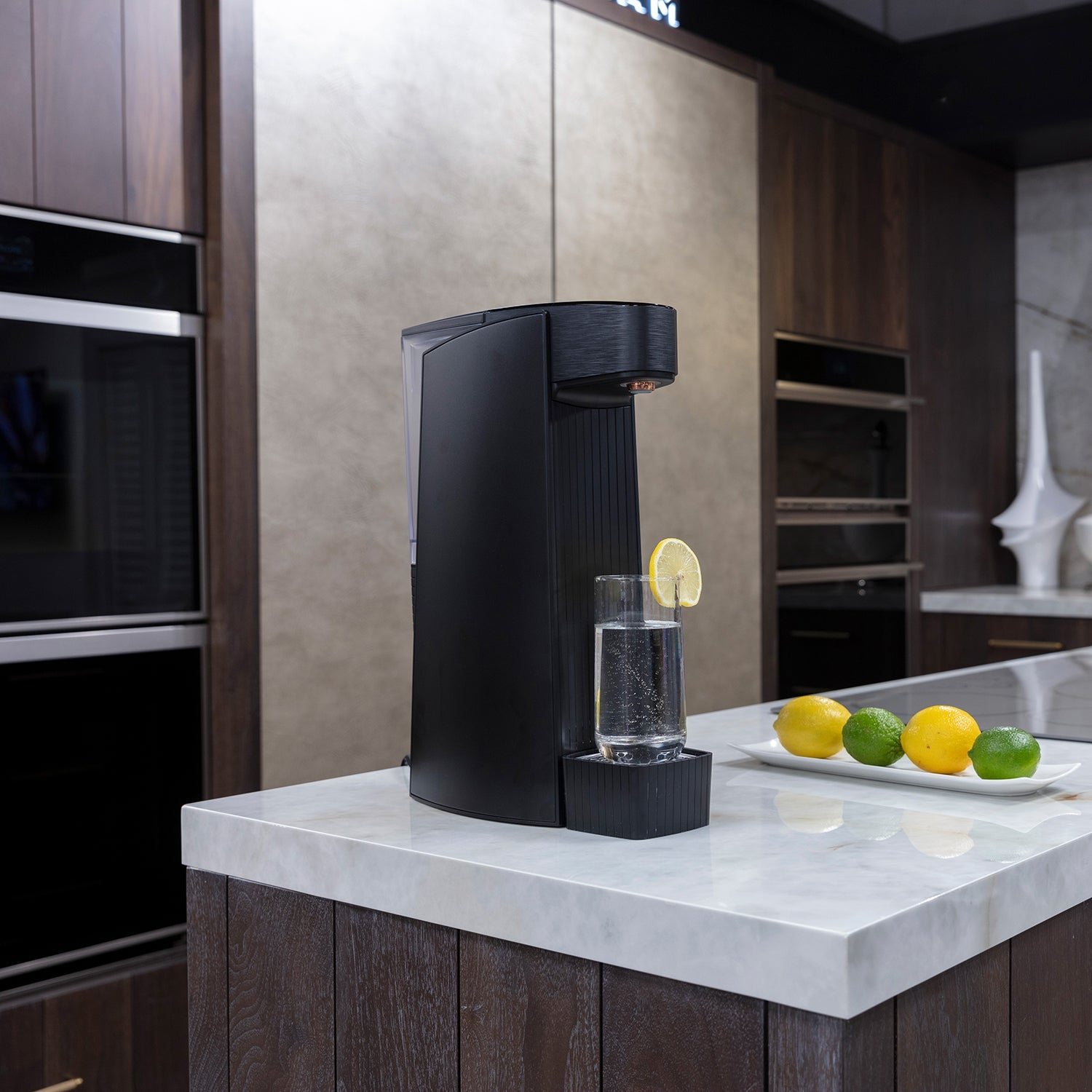 Black sparkling water maker dispensing water with lemon slice on countertop