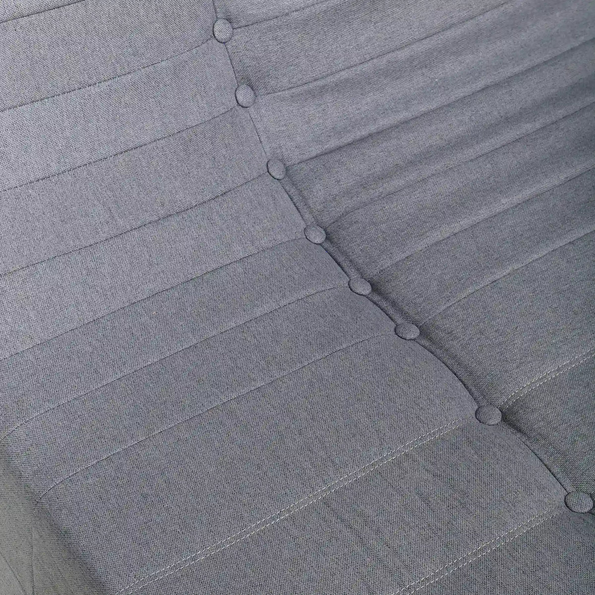 Gray sofa back cushion with button-tufted trim and stitched seams