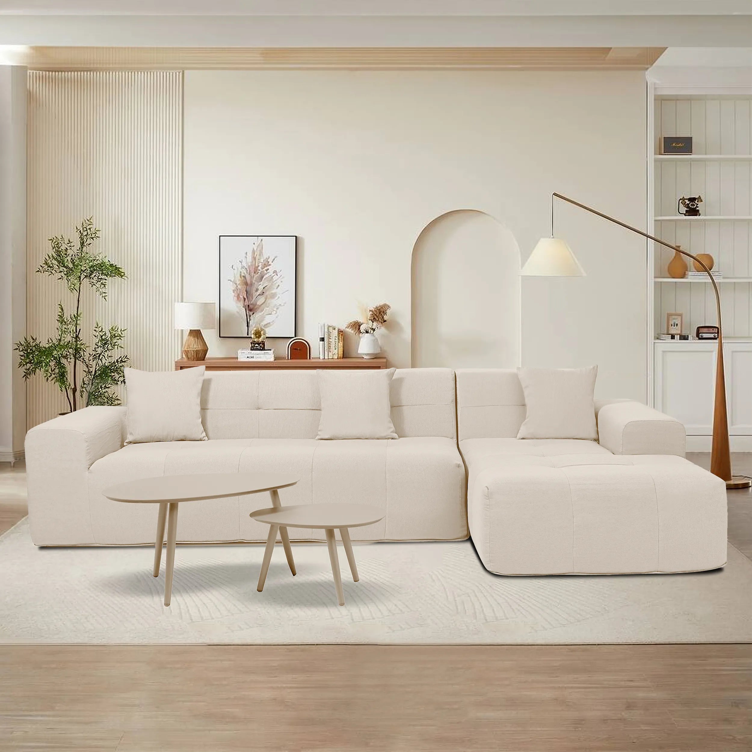 Beige sectional sofa with chaise lounge and two round nesting tables in a living room.