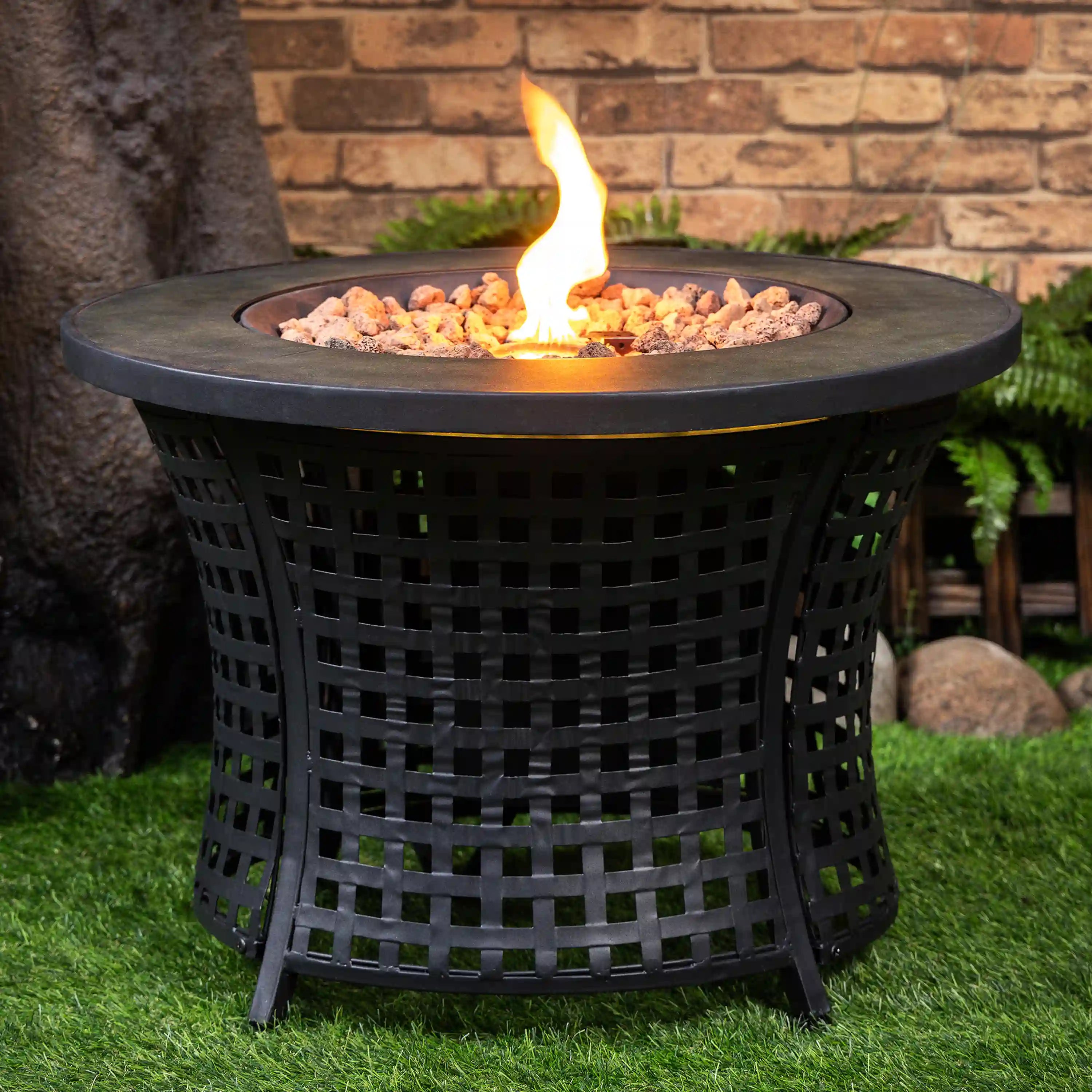Round black propane fire pit table with lattice sides, burning flame over lava rocks