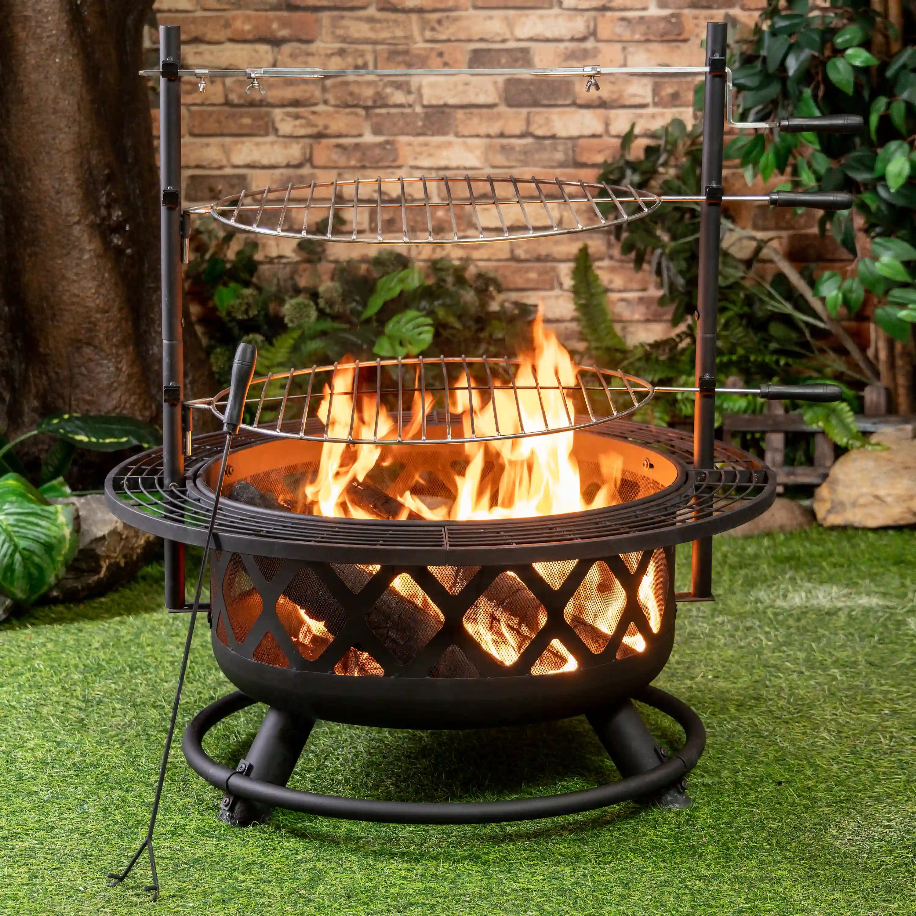 Outdoor steel fire pit grill with two cooking racks and strong flames inside the bowl