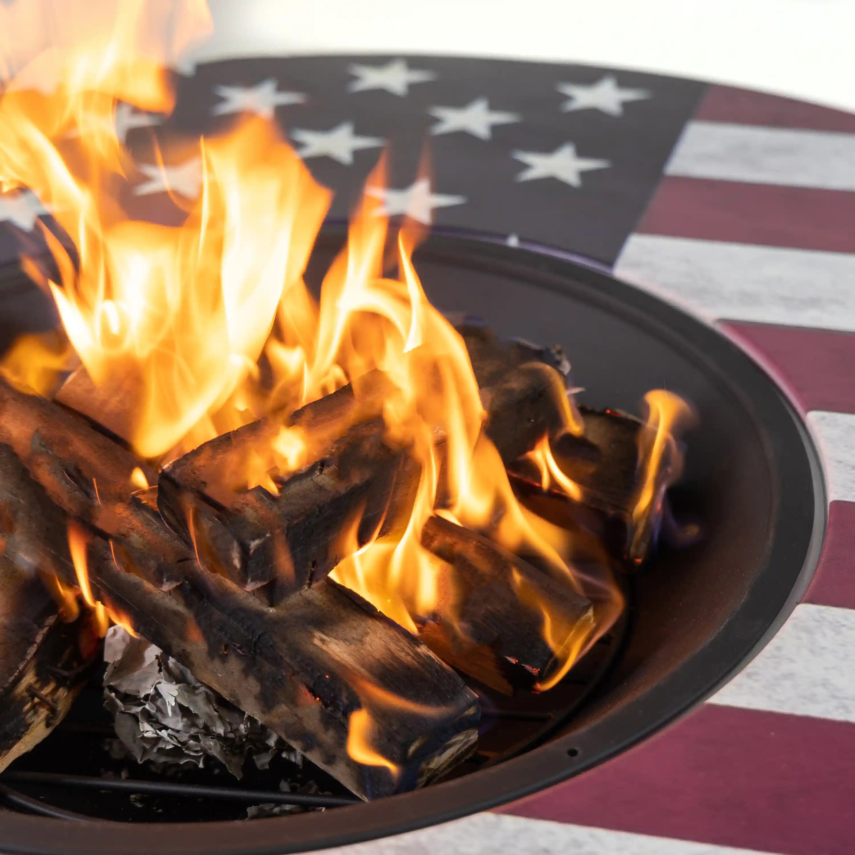 Round fire pit with burning wood in the black steel fire bowl