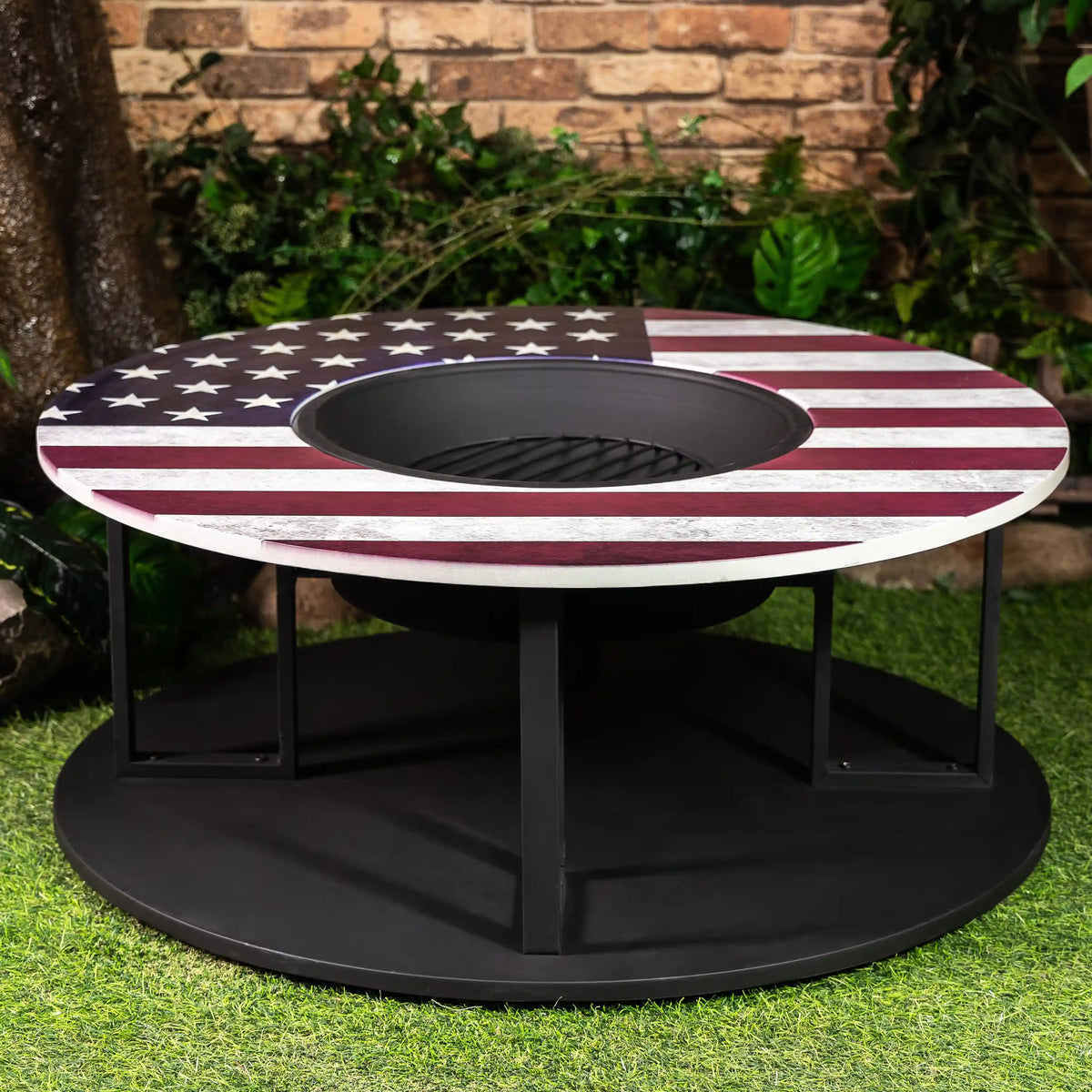 Star-and-stripe round fire pit on black stand with open center and log storage
