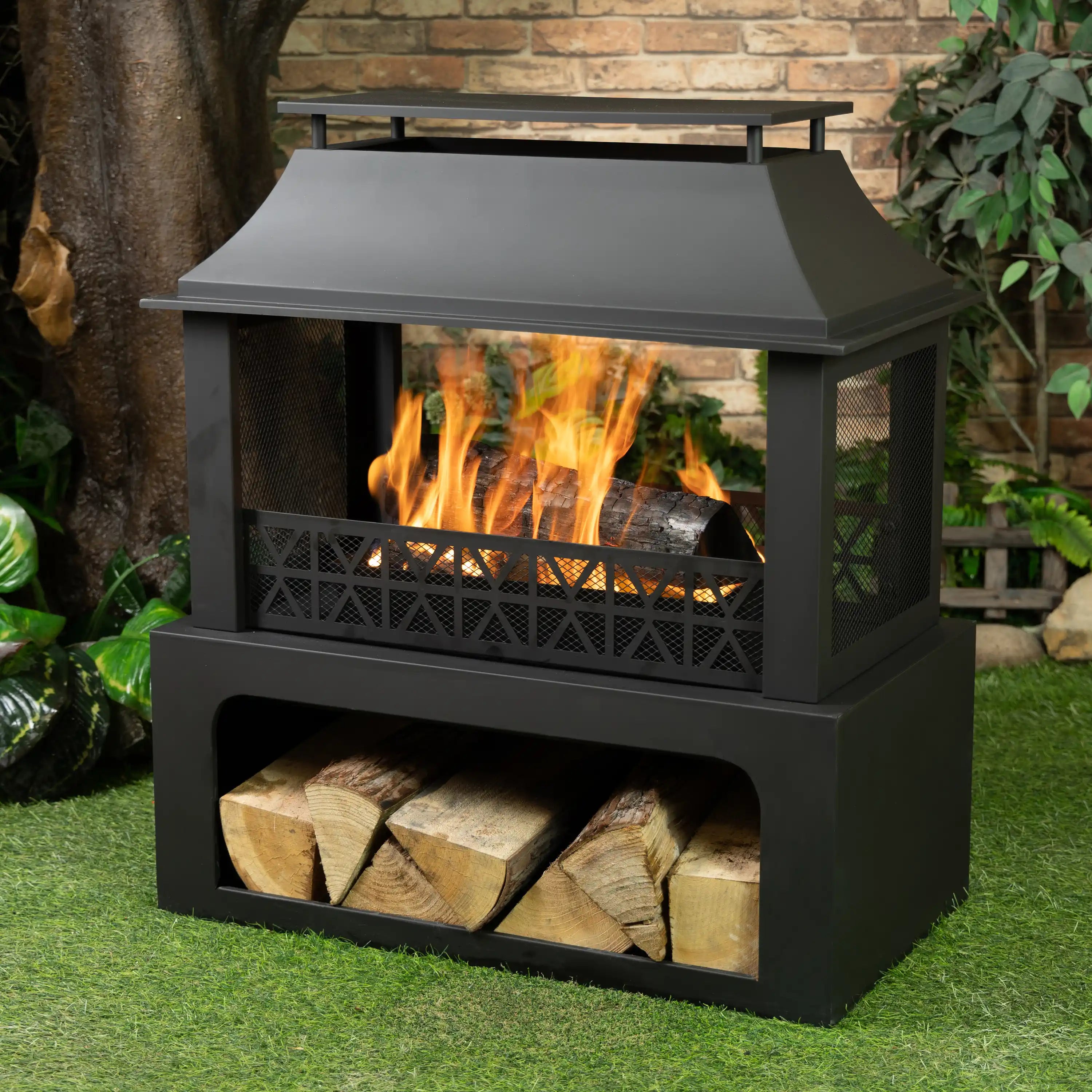 Outdoor steel wood-burning fireplace with flames, log storage drawer, and screen front