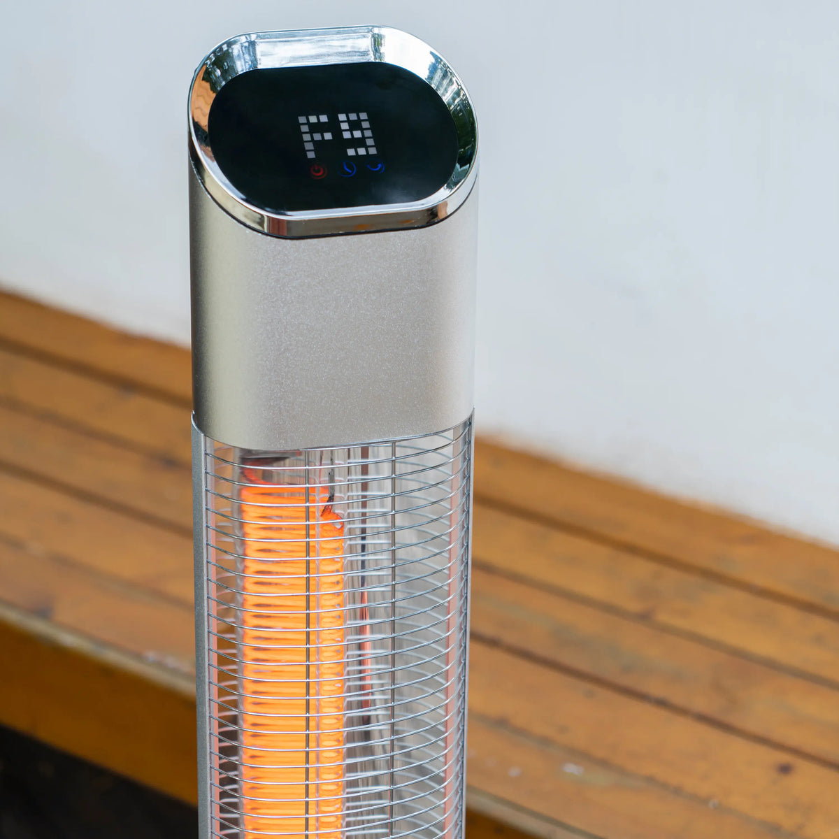 Stainless electric tower heater with glowing infrared tube behind wire front grille