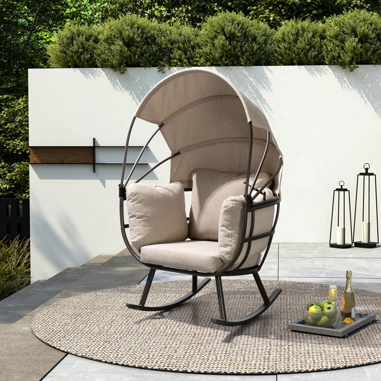 Outdoor rocking patio egg chair with beige cushions, dark frame, and curved canopy