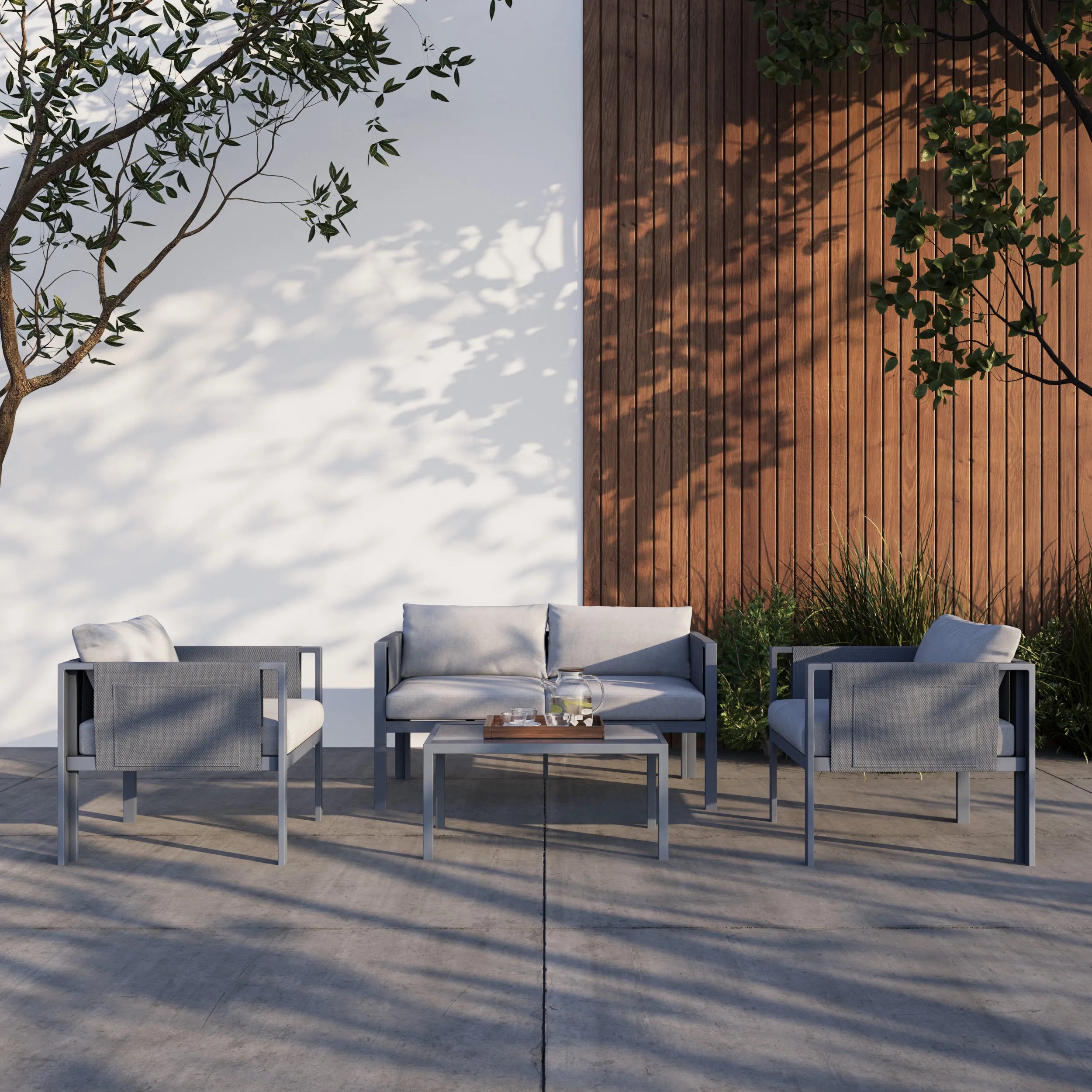 Outdoor seating set with gray loveseat, armchairs, and glass-top table in outdoor setting