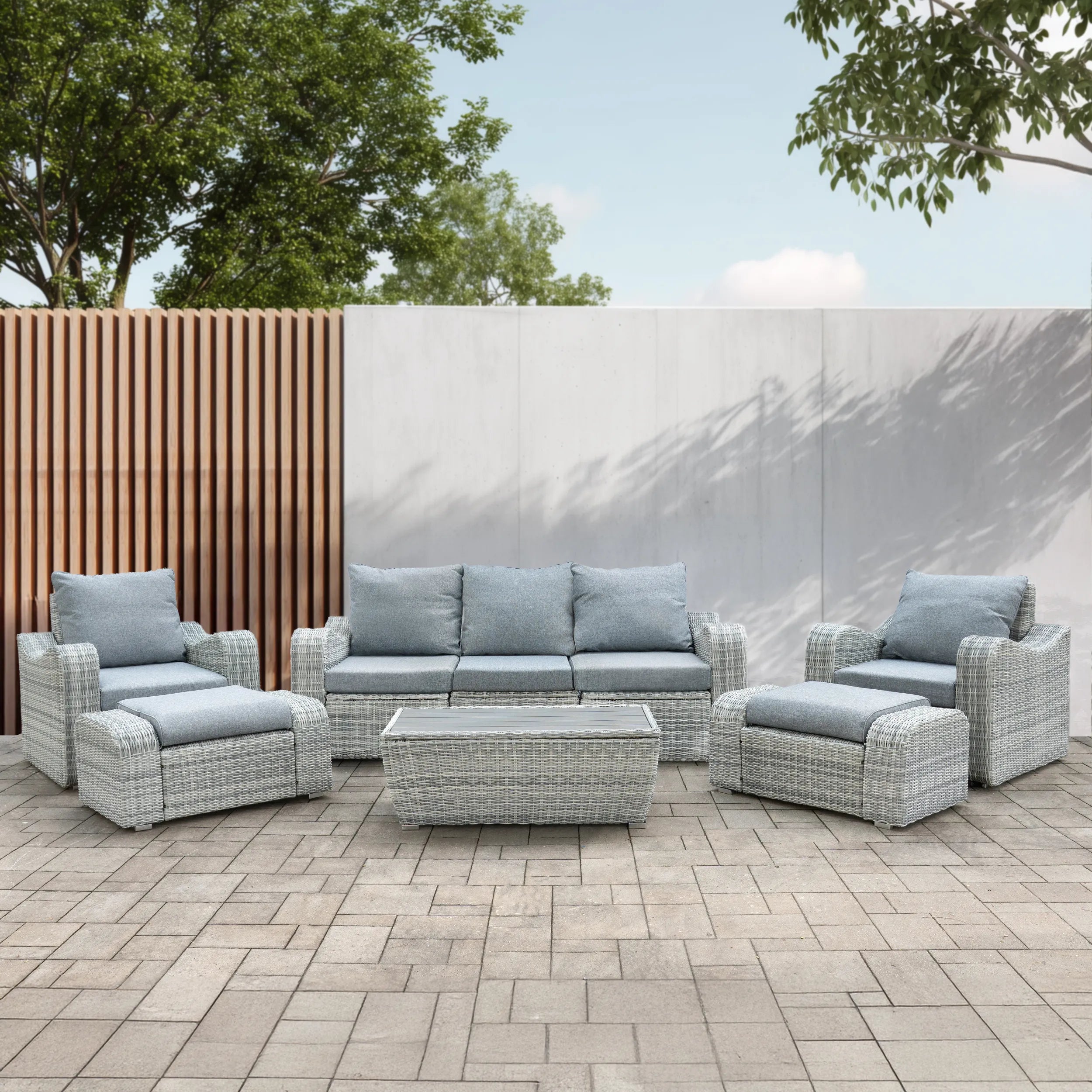 Gray outdoor wicker seating set with sofa, chairs, and glass-topped table