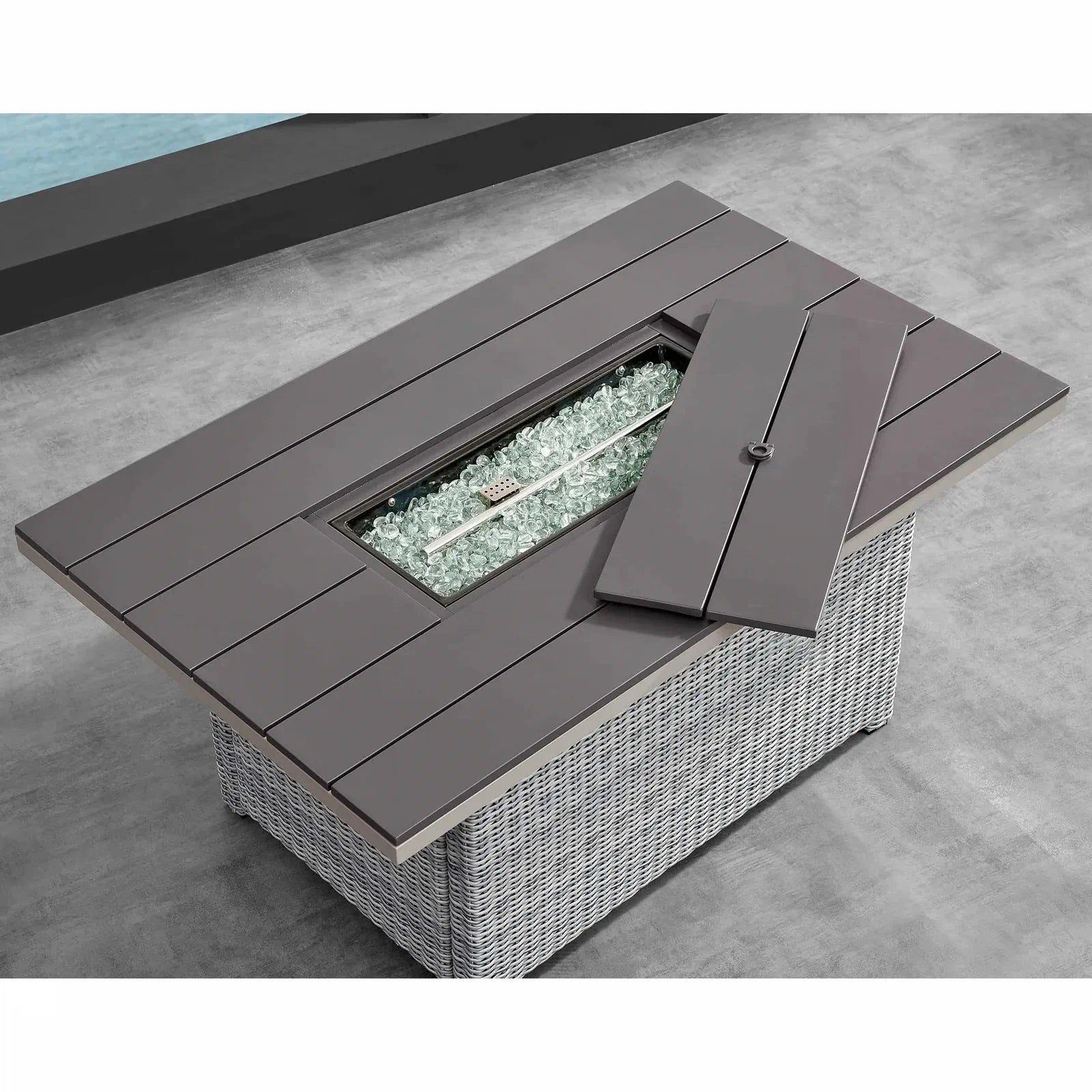 Dark gray firepit table with open lid over clear glass fire media