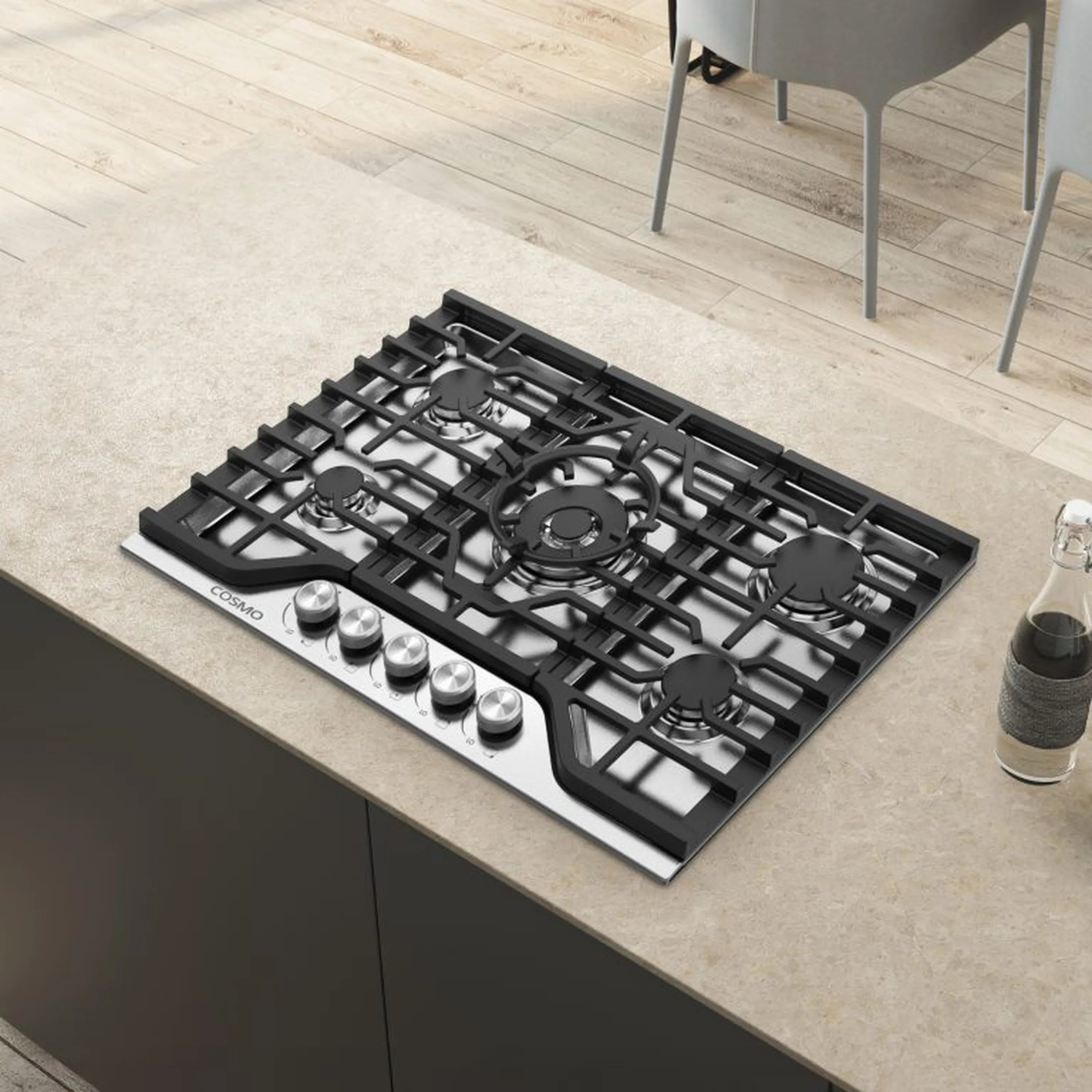 Stainless steel gas cooktop built into countertop with black grates and five burners