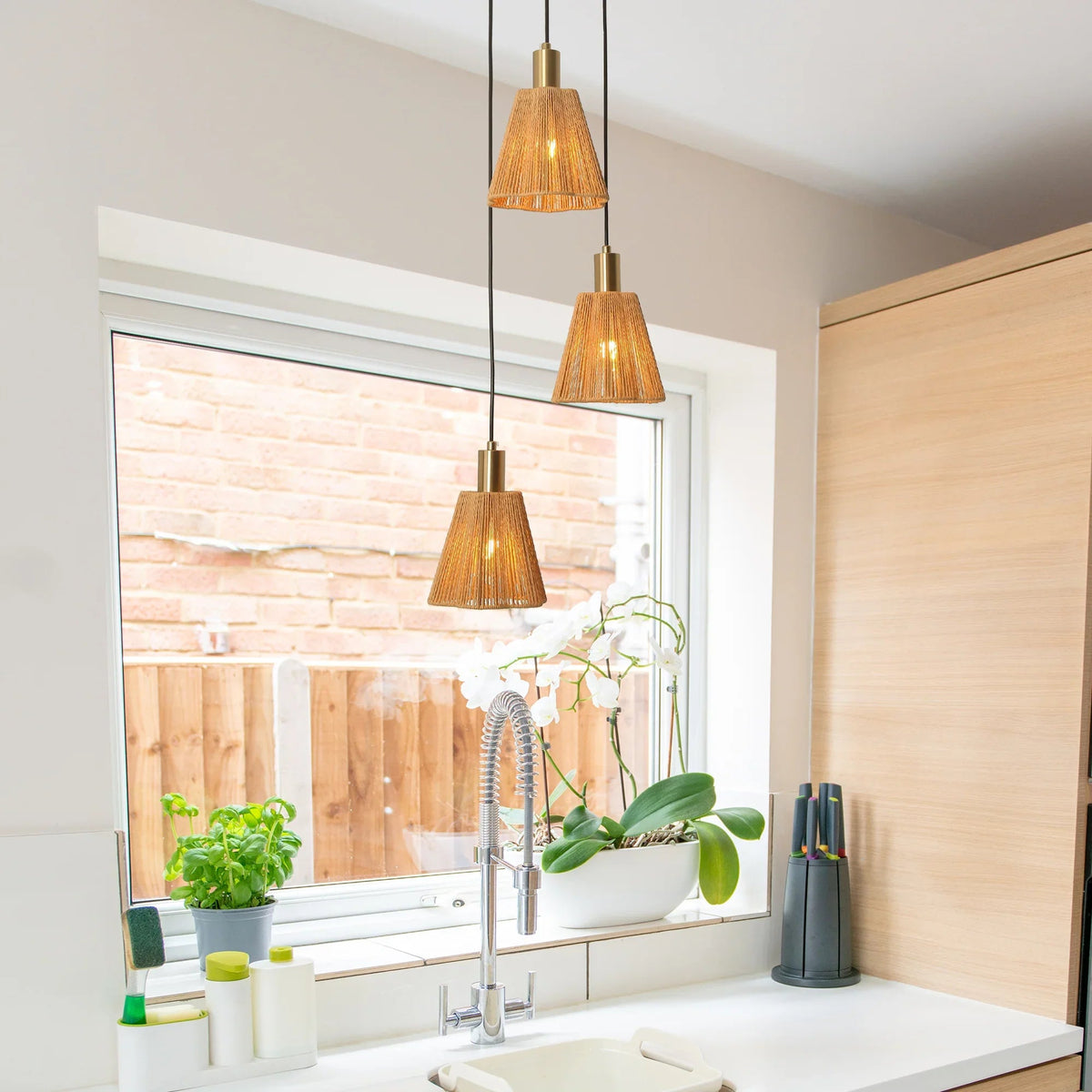 Golden three-light pendant above sink area with amber cone glass shades