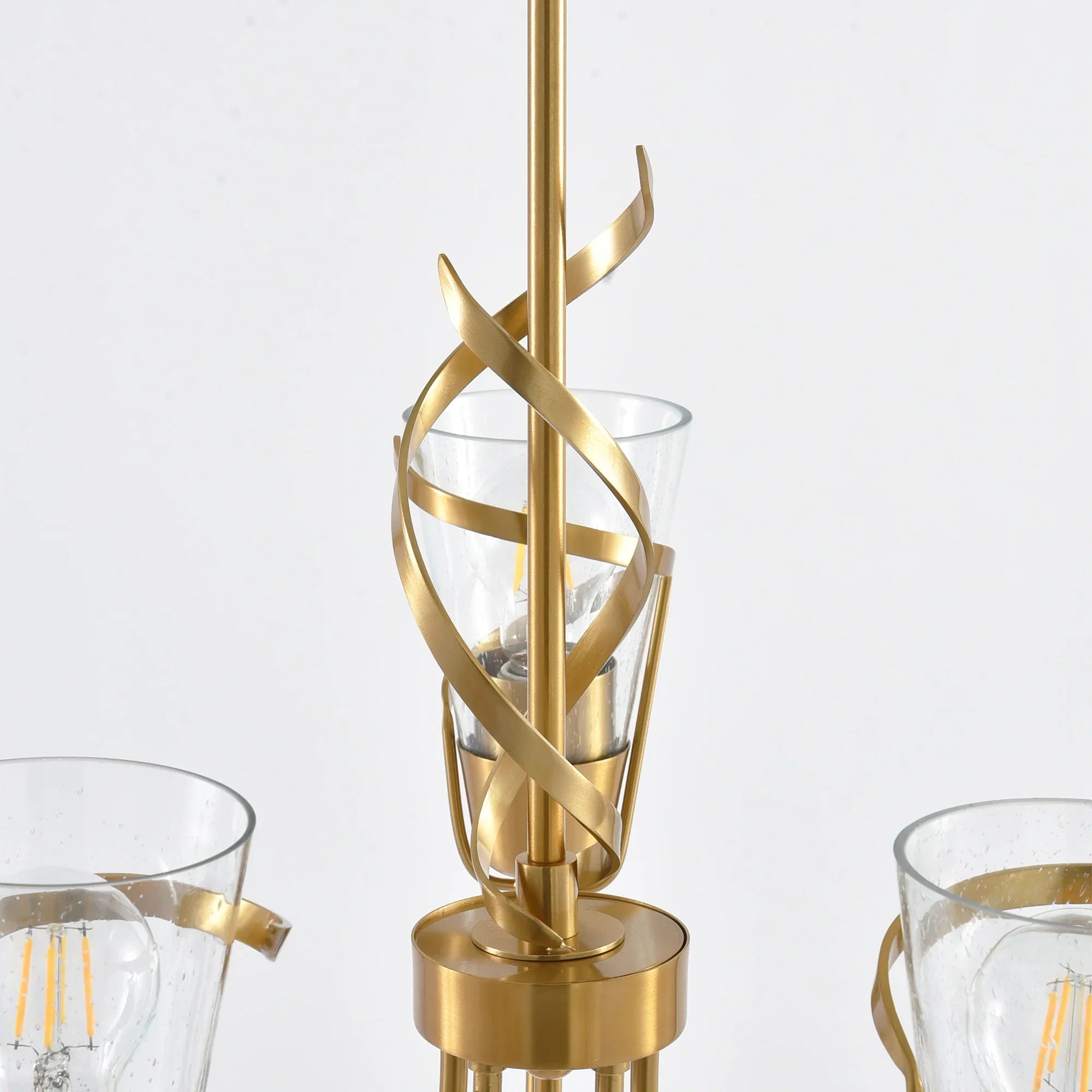 Golden chandelier detail with twisted metal frame and clear glass candle cups